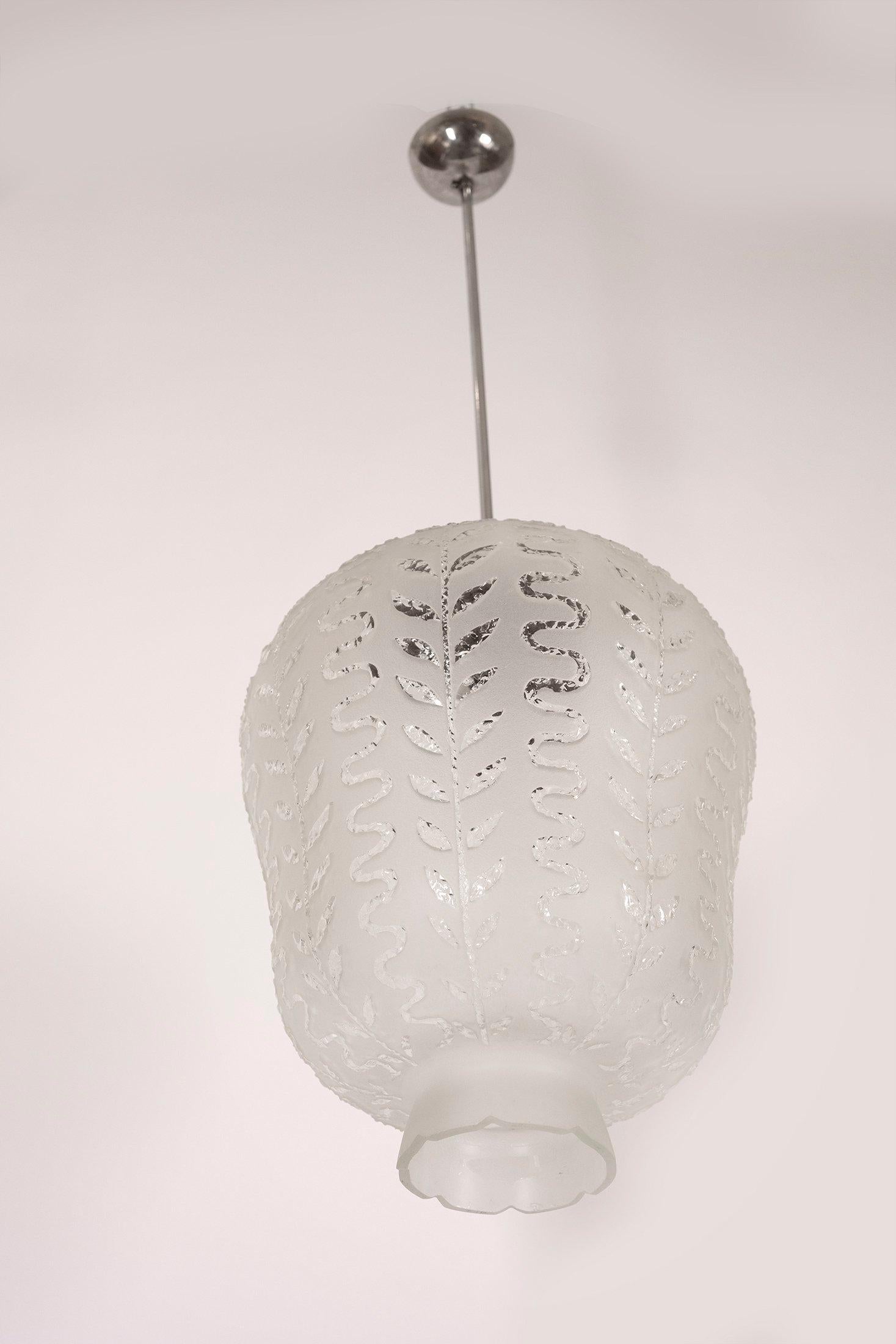 Pendentif en forme de coupe en verre dépoli avec des décorations en relief alternant des feuilles et des vagues sur toute la surface, vers les années 1940. 

Dimensions de l'abat-jour : 16