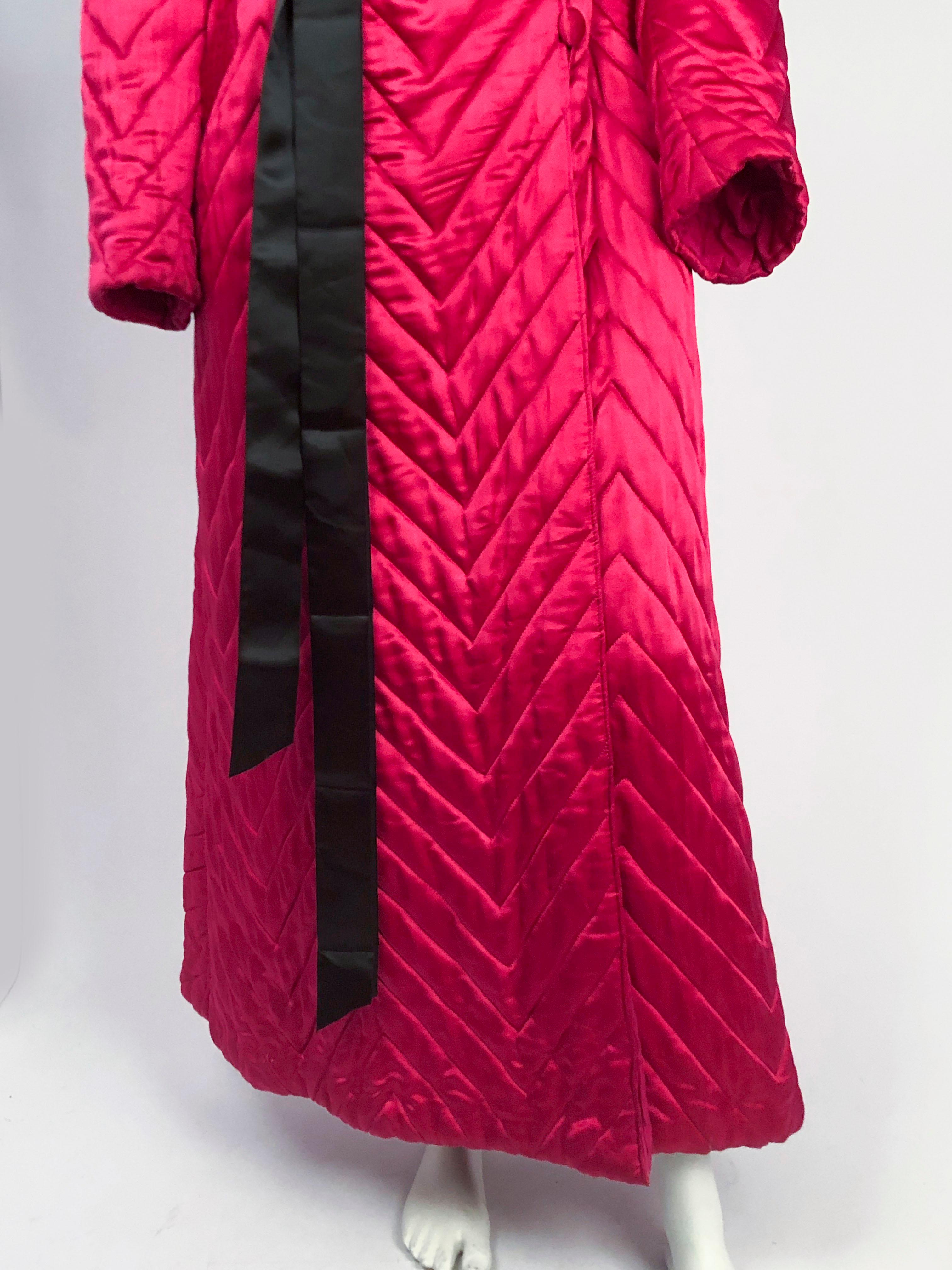 1940s Fuchsia Silk Satin Quilted Robe that has a silk lining, oversized peak lapel collar, covered buttons, and a long black sash