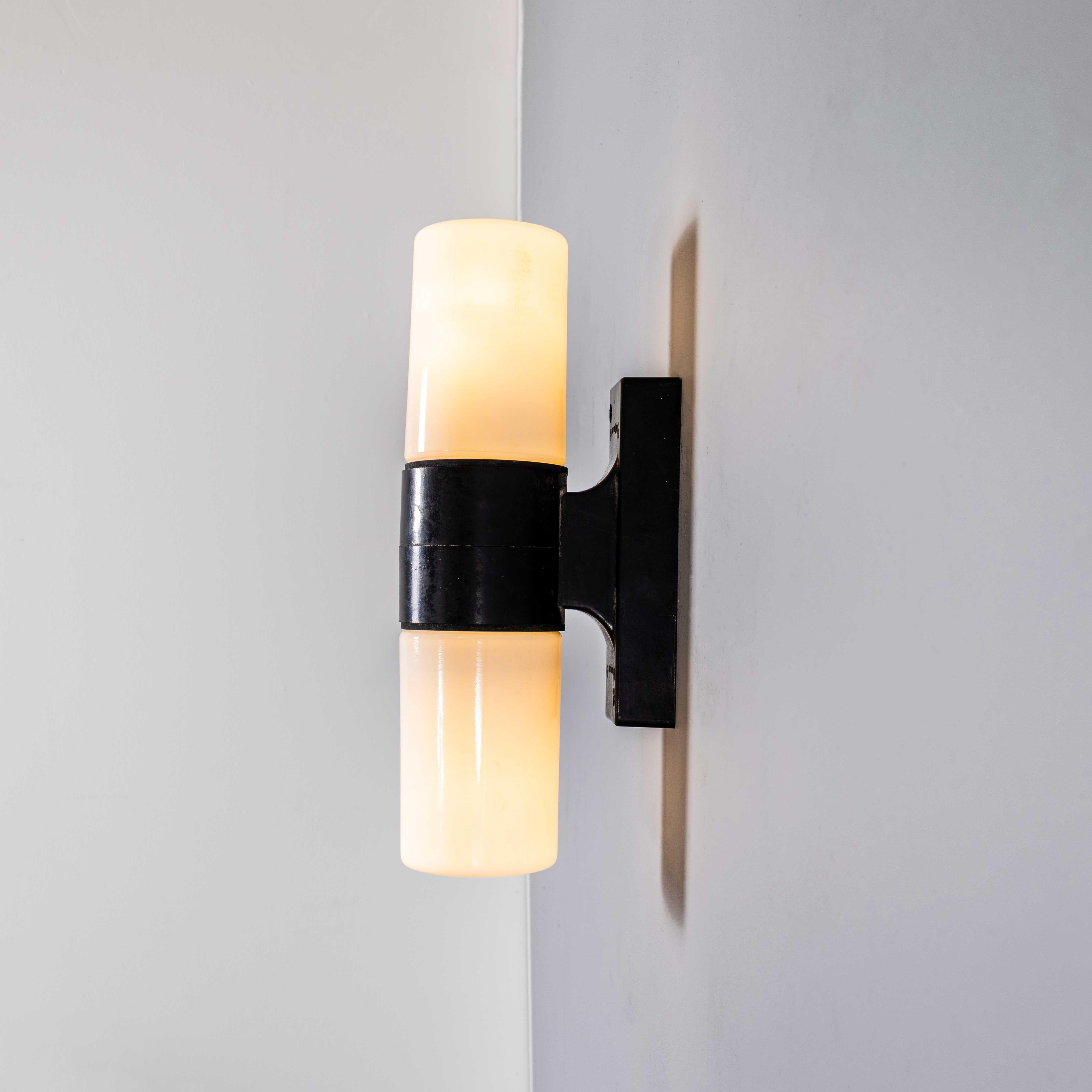 Lampade da parete a bastone in vetro opalino e bachelite degli anni '40. 
Le lampade hanno un corpo solido in bachelite (autoisolato) e due paralumi opalini a cilindro che si avvitano sulle due lampadine separate. Ogni lampada è stata pulita e