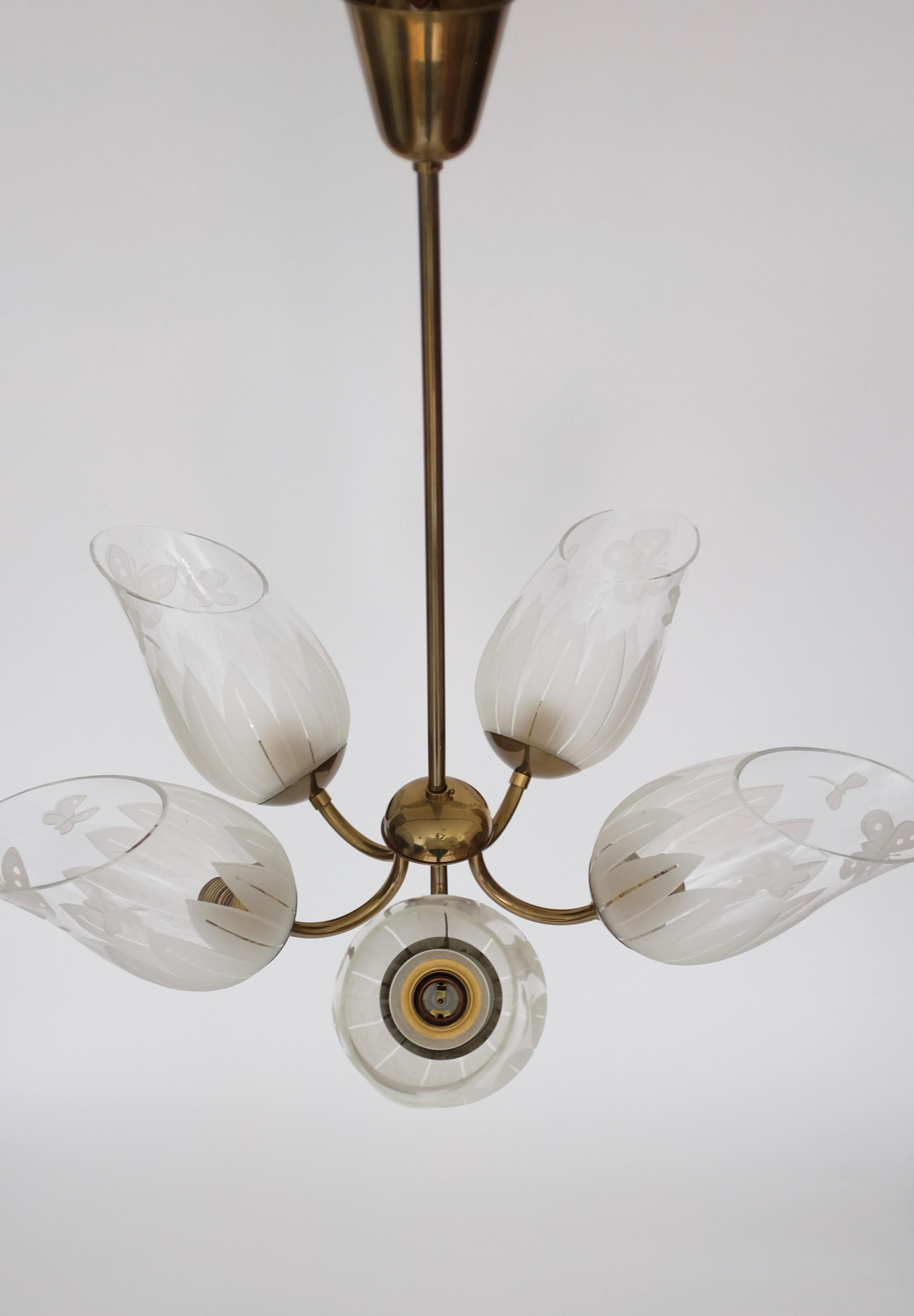 Impressive Glass and Brass Chandelier by Bo Notini for Glössner, Sweden, from the 1940s. Consisting of 5 individual lamp arms with beautiful glass etched lanterns with organic leaf and butterflies details. In a very good condition with the brass in