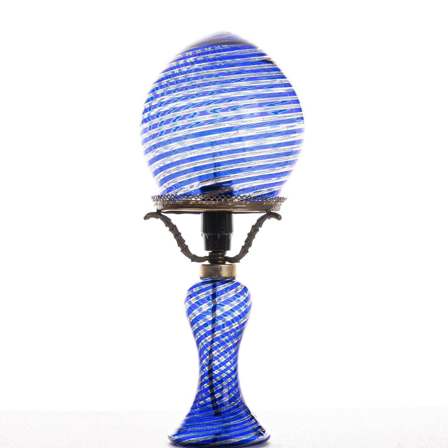 This is a highly creative lamp from designer Venini. Drawing on Murano's reputation for unique and colorful glasswork, the blue, flowing design used here gives a soft illumination, complementing the flowing lines on the base and shade.
We have a