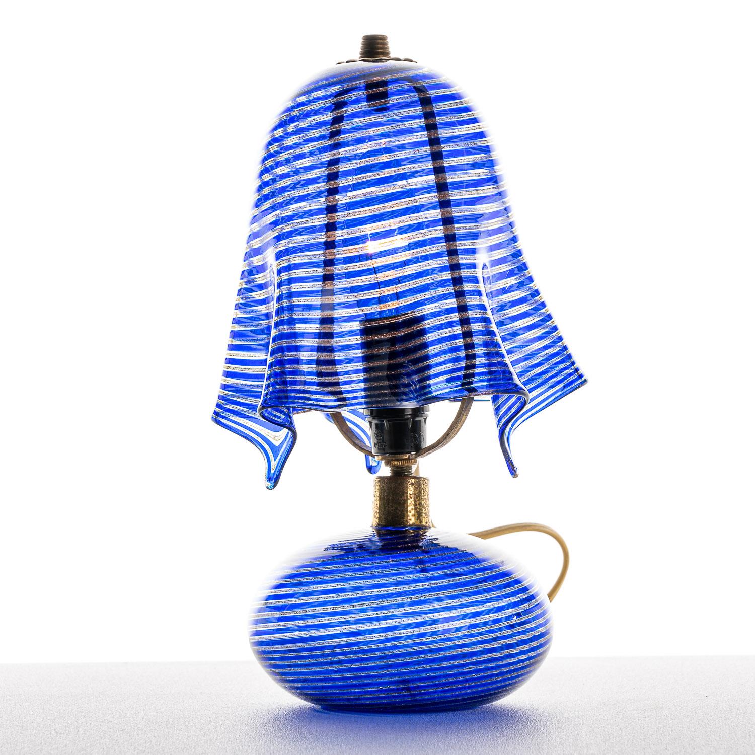 This is a highly creative lamp from designer Venini. Drawing on Murano's reputation for unique and colorful glasswork, the blue, flowing design used here gives a soft illumination, complementing the flowing lines on the base and shade.