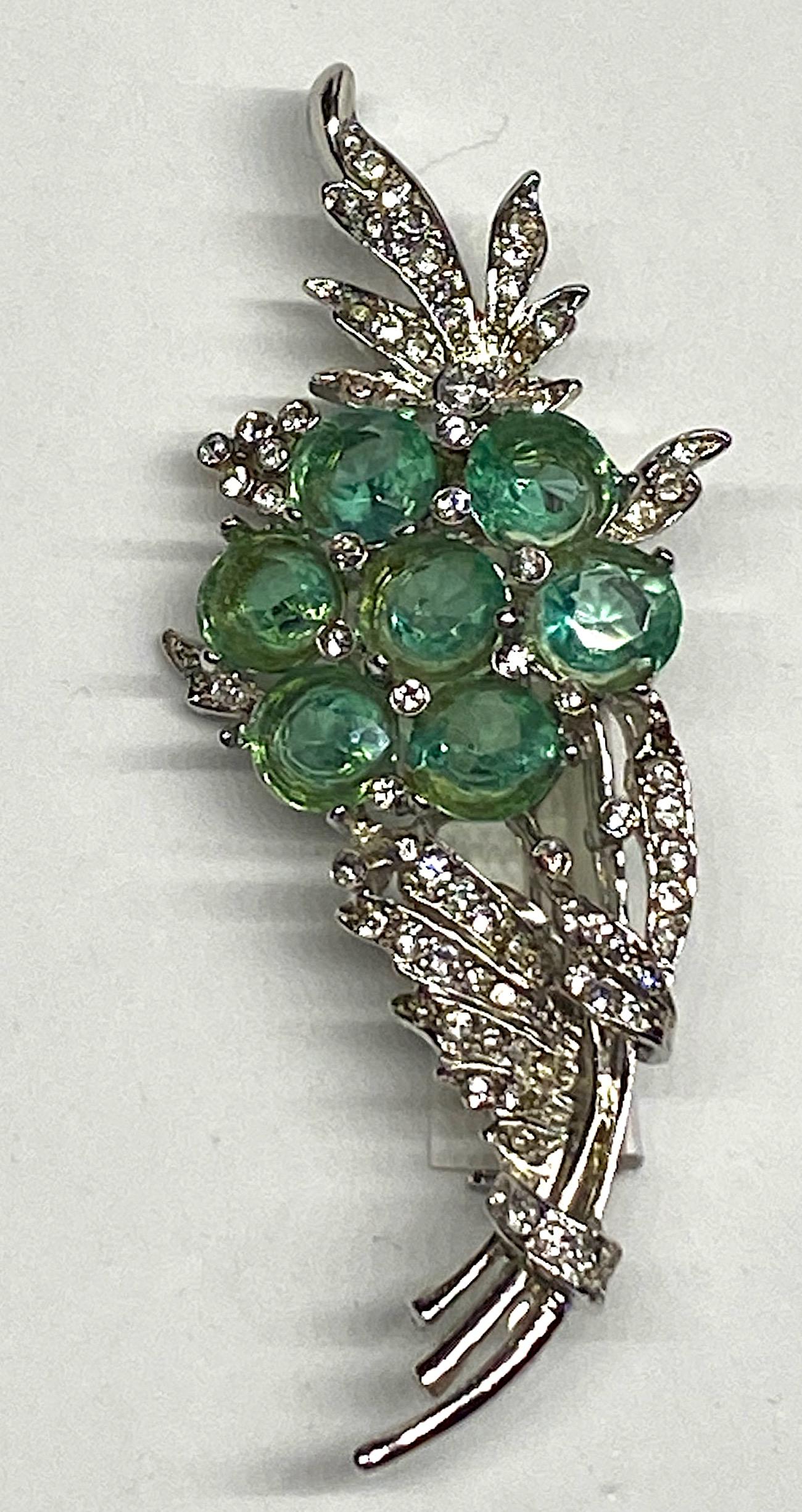 A lovely and in excellent condition green crystal flower brooch from the 1940s. Attributed to the jewelry company Reja from the design, construction and rhodium parting of the setting and use of the light aqua green crystal stones typically used by