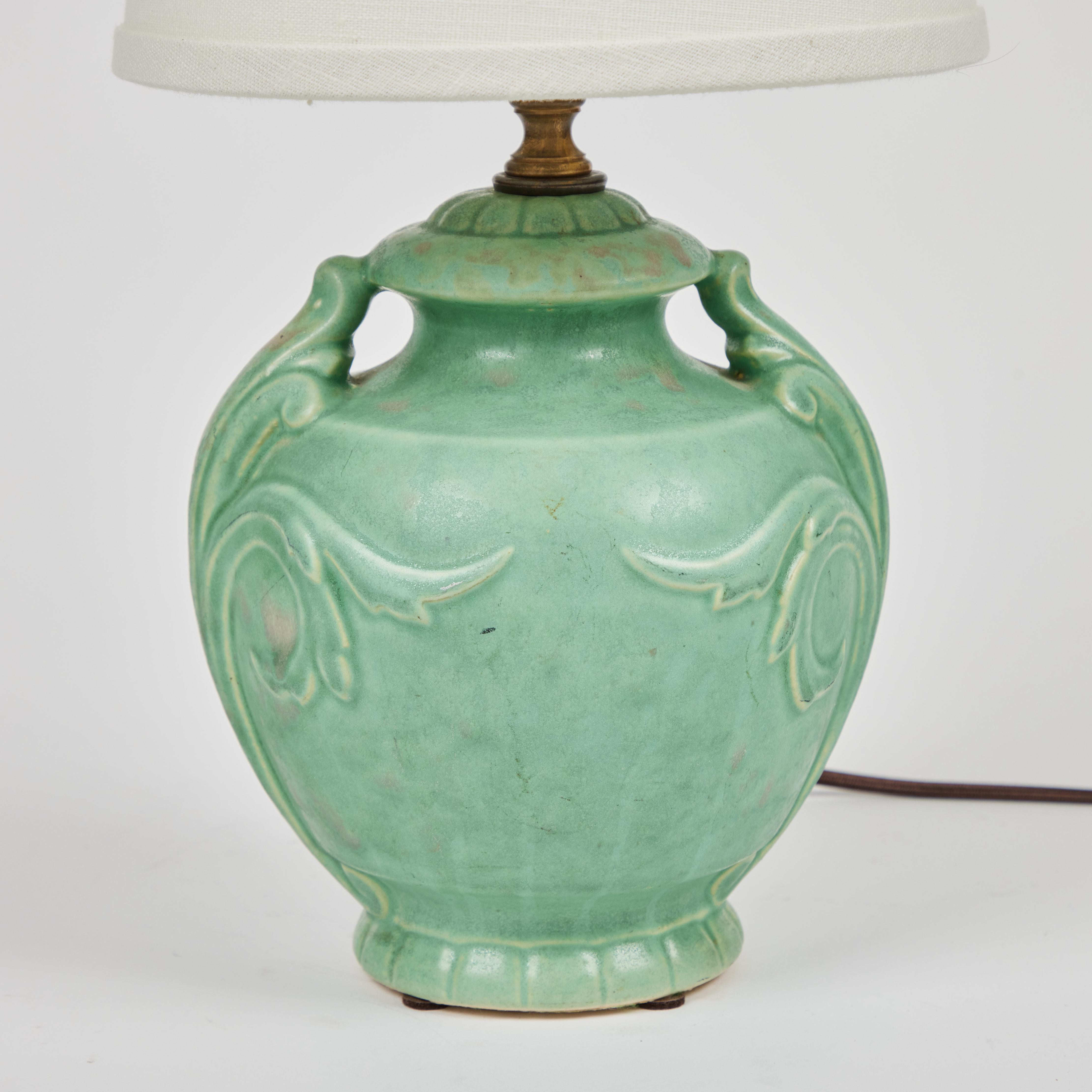 We love this charming 1940's small pottery urn style lamp with a rich matte pale green glaze. It has been newly rewired and has a new custom linen shade.

It measures: 6.5