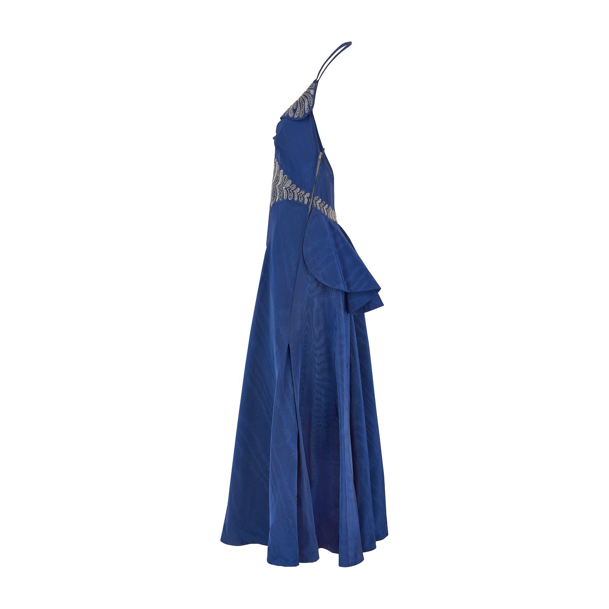 Questo incredibile abito di alta moda è stato disegnato negli anni '40 ma, ahimè, l'abito ha perso le sue etichette. Realizzato con la più bella e spessa seta moiré in blu indaco, è tagliato con uno scollo alla caviglia e una sensuale scollatura