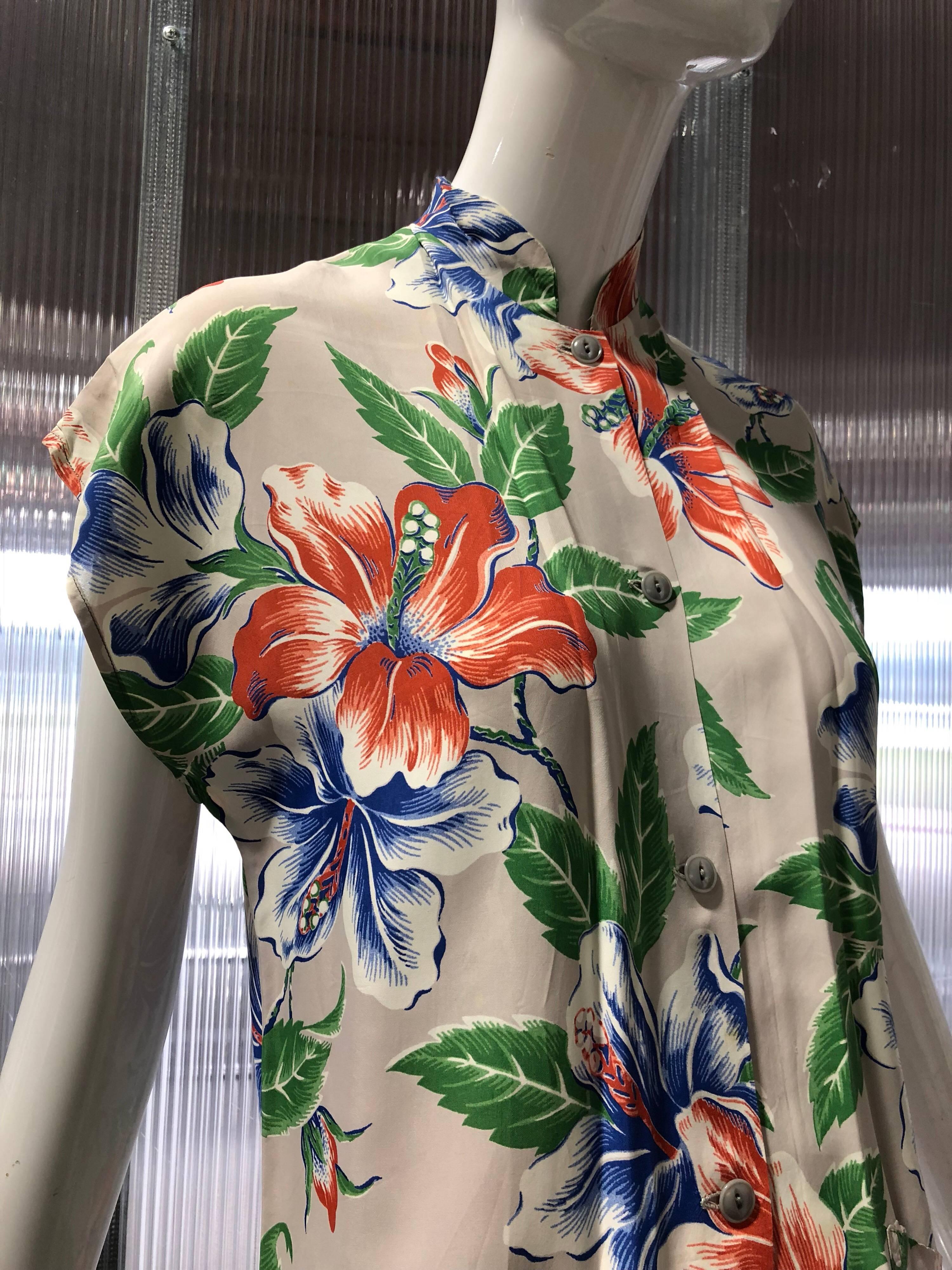 A lovely 1940s Wakiki Fashion Hawaiian tropical hibiscus print on slate gray background makes this Nehru-collar blouse with side pockets a standout!  
