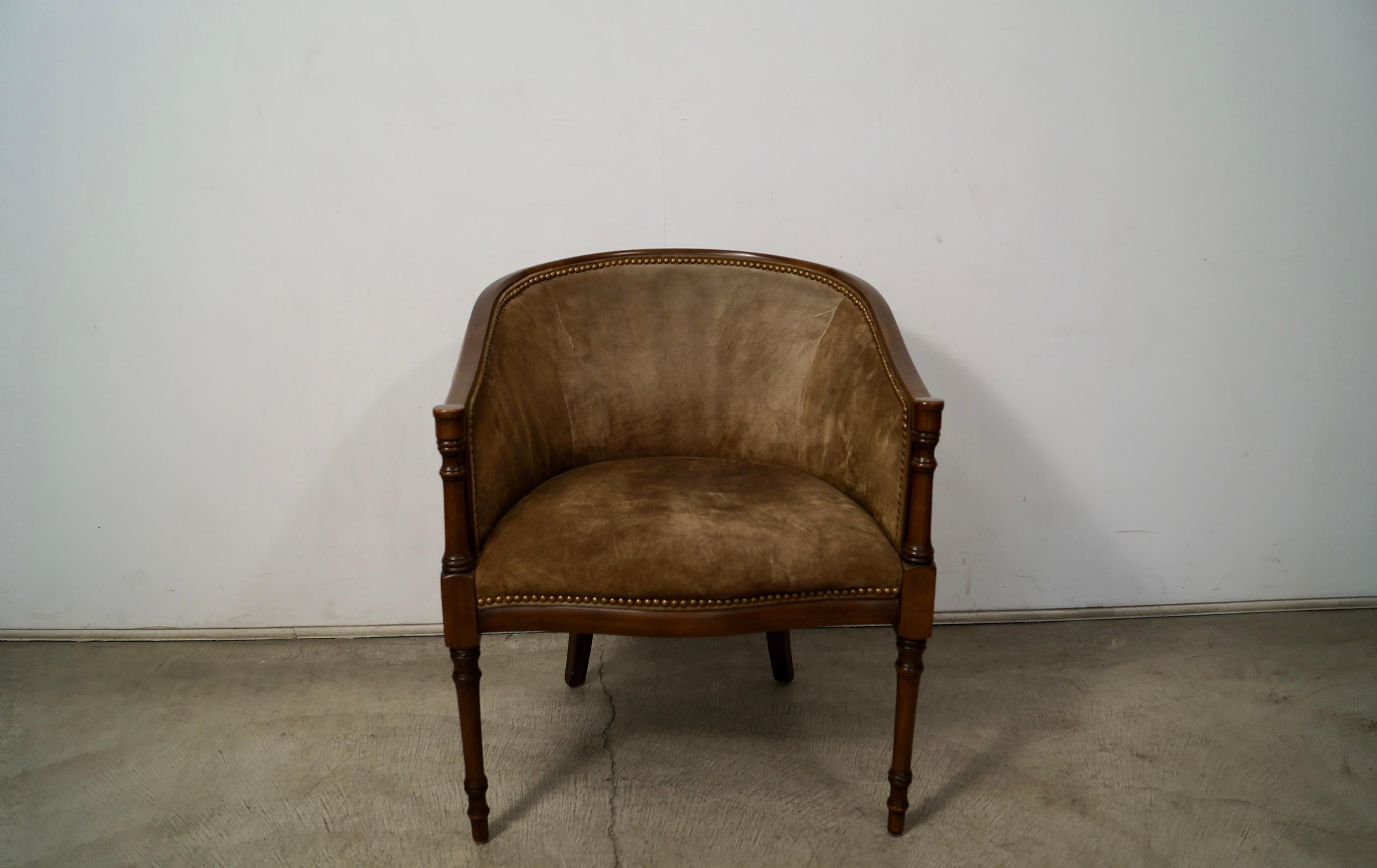Vintage Hollywood Regency barrel-back arm chair for sale. Was previously reupholstered in a brown leather suede. It has a solid walnut frame, and has a beautiful walnut finish. The chair is in excellent condition. The suede has had two repairs to it