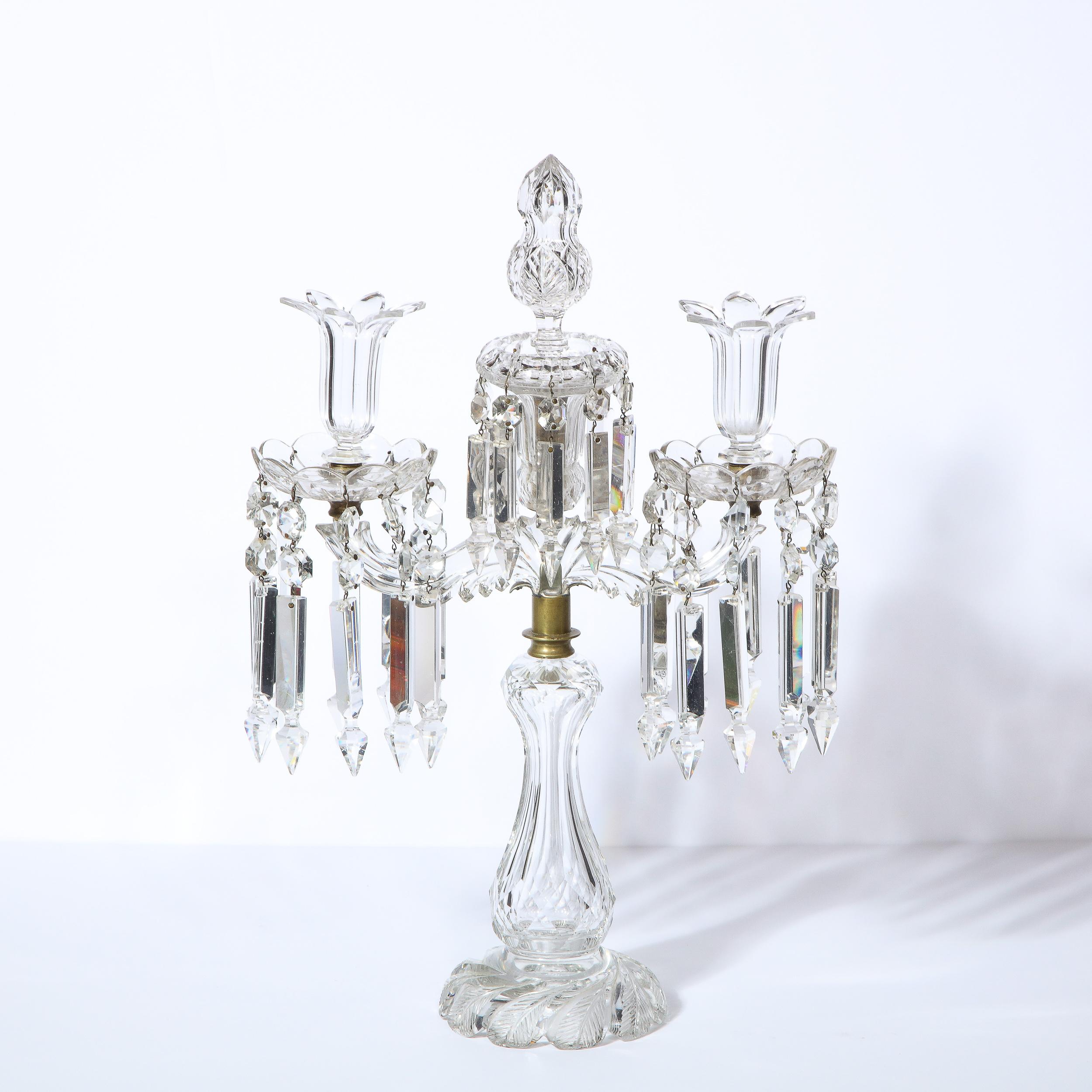 This glamorous 1940s Hollywood Regency girandole/ candelabra was realized in the United States circa 1940. It features a circular channeled base with foliate engravings that ascends into an undulating body with diamond forms faceted into the glass.