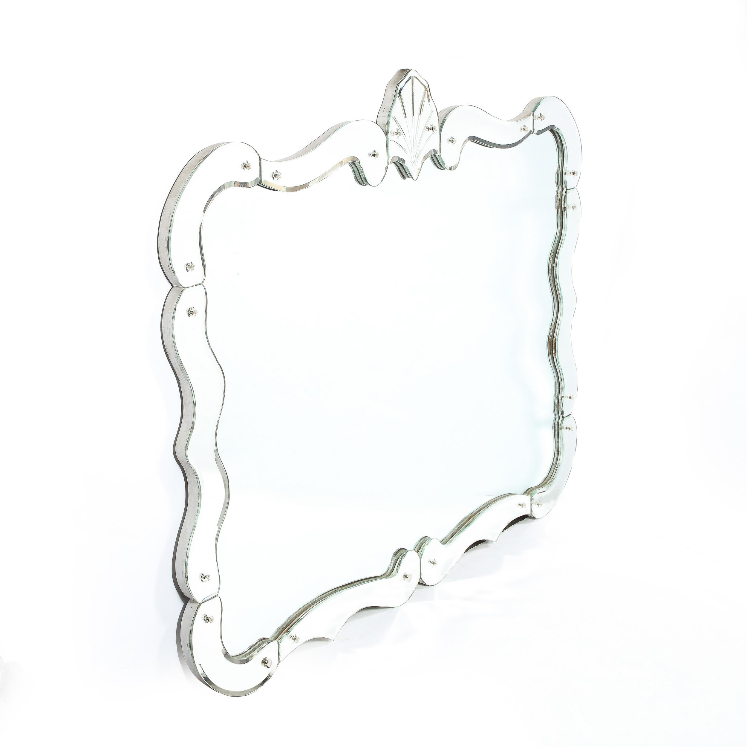 This elegant 1940s Hollywood mirror was realized in the United States circa 1940. It features a rectangular form with rounded edges and bevel detailing. The perimeter of the piece is decorated with undulating segments (also in plain mirror), secured