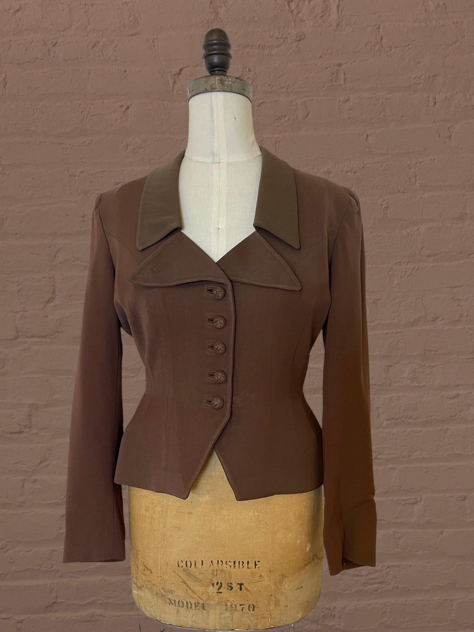 Vintage brown wool blazer. fashionable collar. cinched waist. long sleeves. brown & white striped lining. covered buttons. has shoulder pads. 

A beautifully constructed jacket.

A wonderful piece of mid century fashion history! Make a statement in