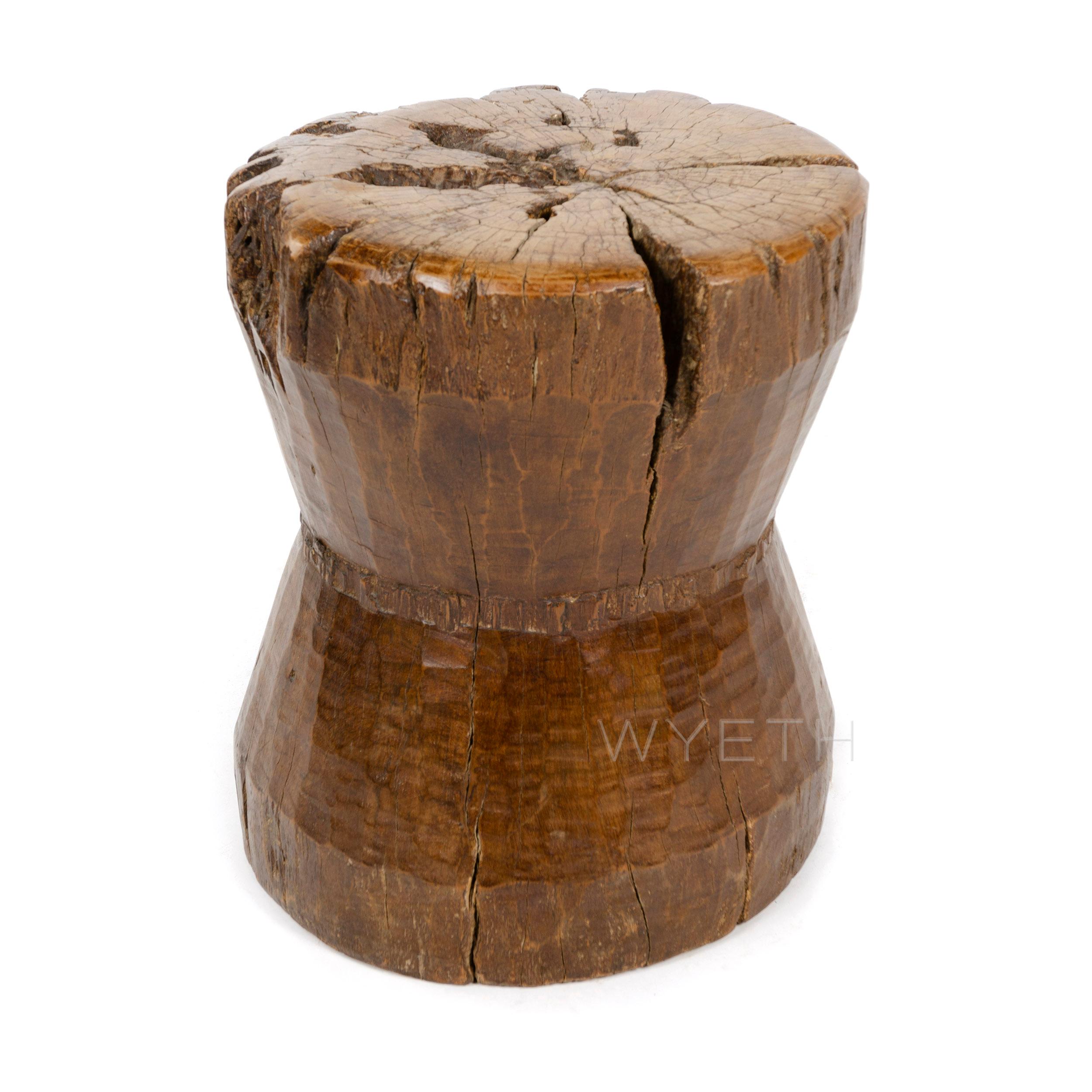 An Indonesian stool with a decorative cinched waist made from hand carved mahogany.