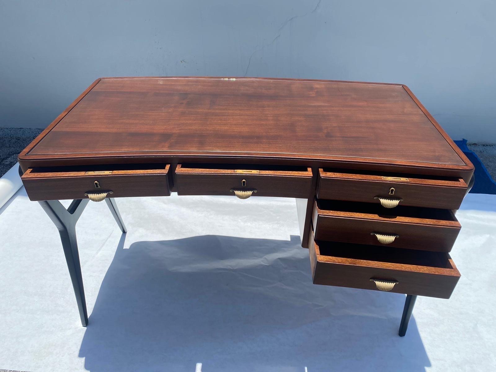 Truly OUTSTANDING slightly curved Italian desk with sculptural legs and brass pulls (original desk key).  The beautiful Walnut plateau has been restored and new glass top blotter.  It is beautiful from ALL sides and great scale.  THIS ITEM IS