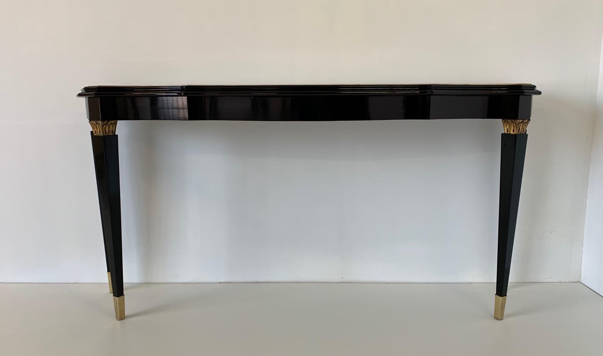 An Italian 20th century ebonized console table in the style of Paolo Buffa with brass tips and carved decorations in gold leaf.
Marble top.
Completely restored.