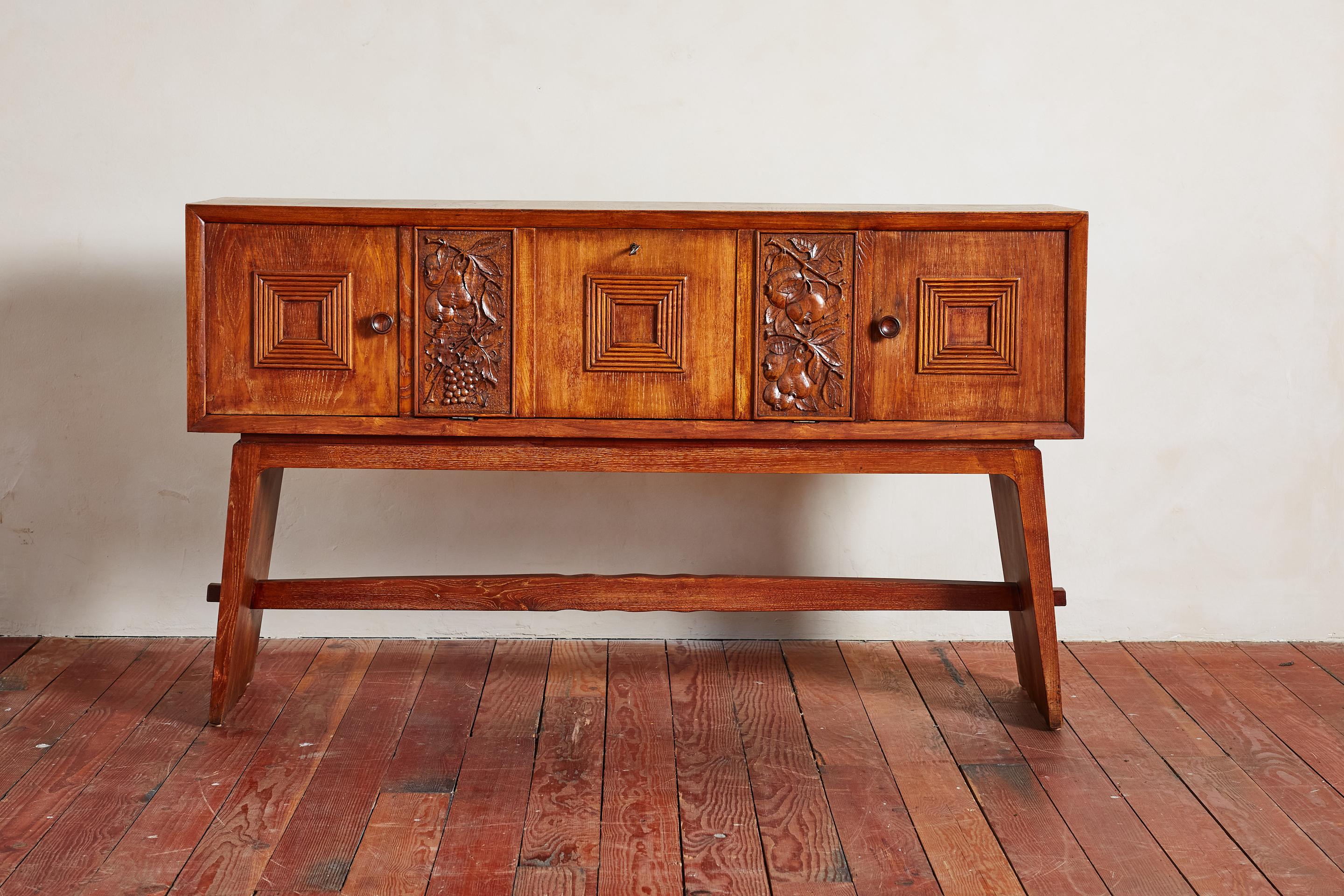 1940's Italian sideboard cabinet with beautiful carved fruit motif

Two side doors with shelves and locked center compartment with pull out door, key included 

Beautiful patina. Angled legs with with cross joint detail. 

Wonderful and unique piece.