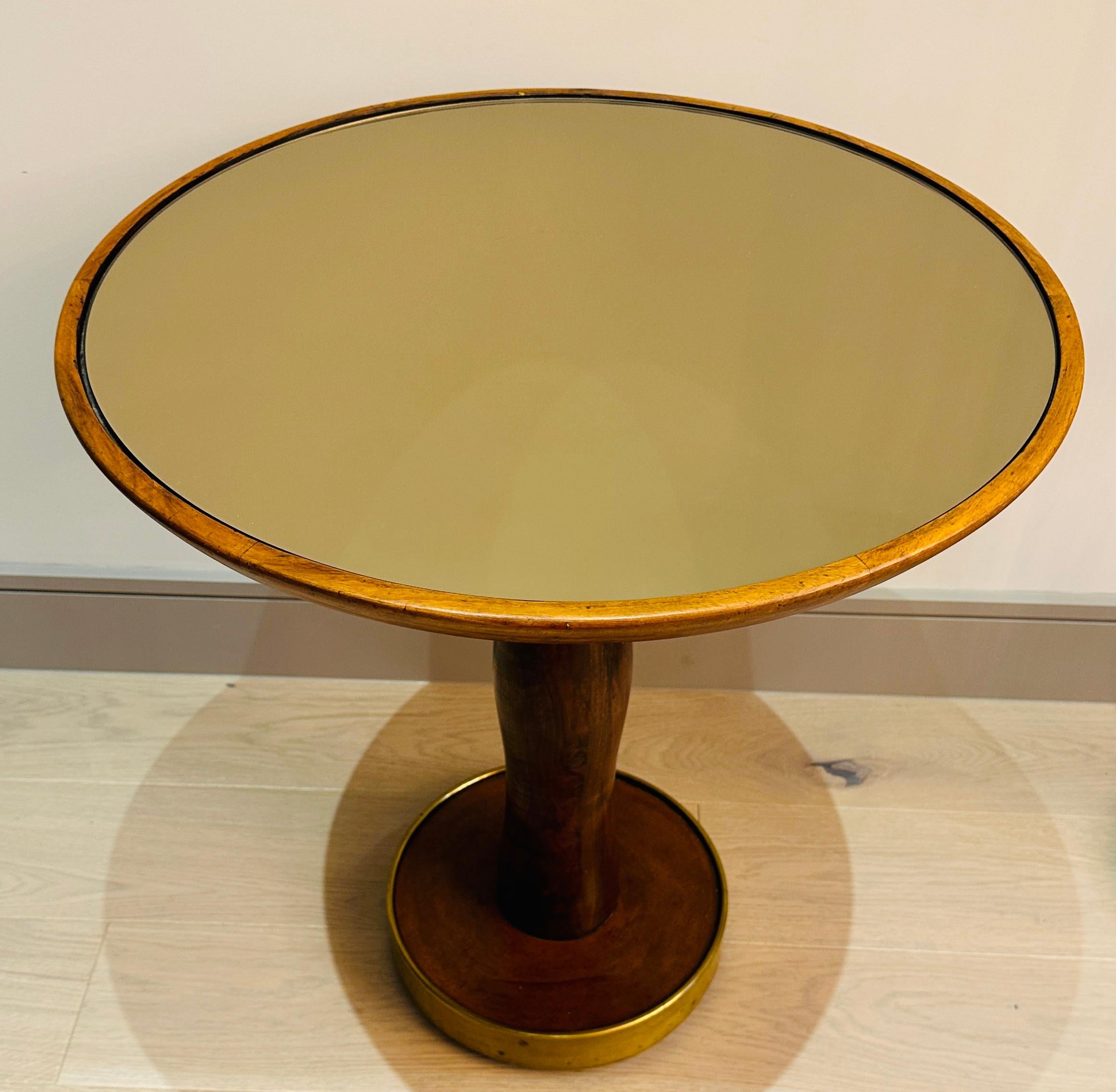 A beautiful organic 1940s Italian circular stained walnut side table with a bronzed glass inset table top and brass base.  The replacement bronzed mirror is inset into the table top wooden edged frame which is secured onto an organic shaped pedestal