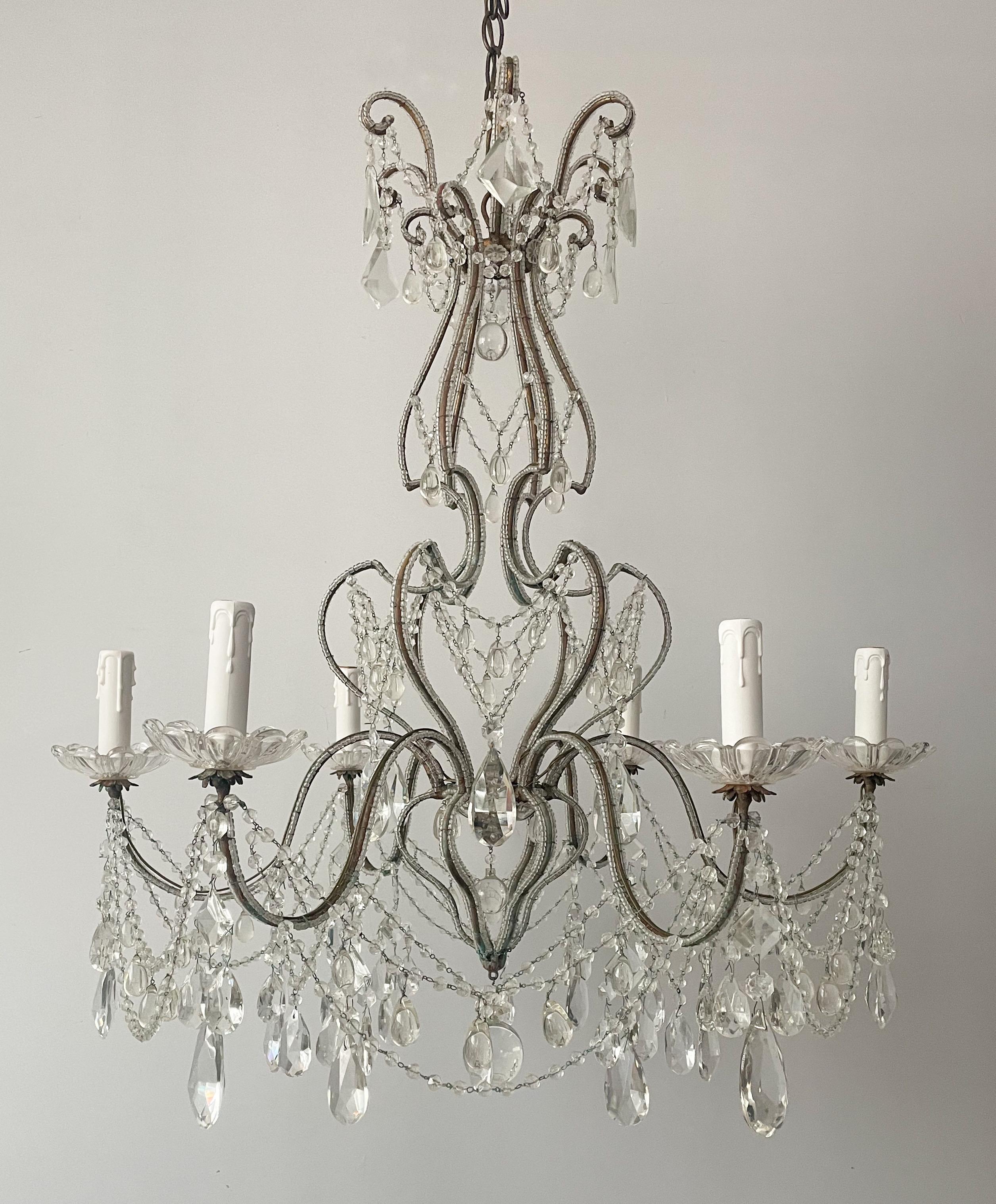 Graceful, Italian 1940s gilt-iron and crystal beaded chandelier.

The chandelier consists of a very shapely iron frame with a gilt finish that has acquired a pleasing verdigris patina through the decades. A tasteful assortment of crystal