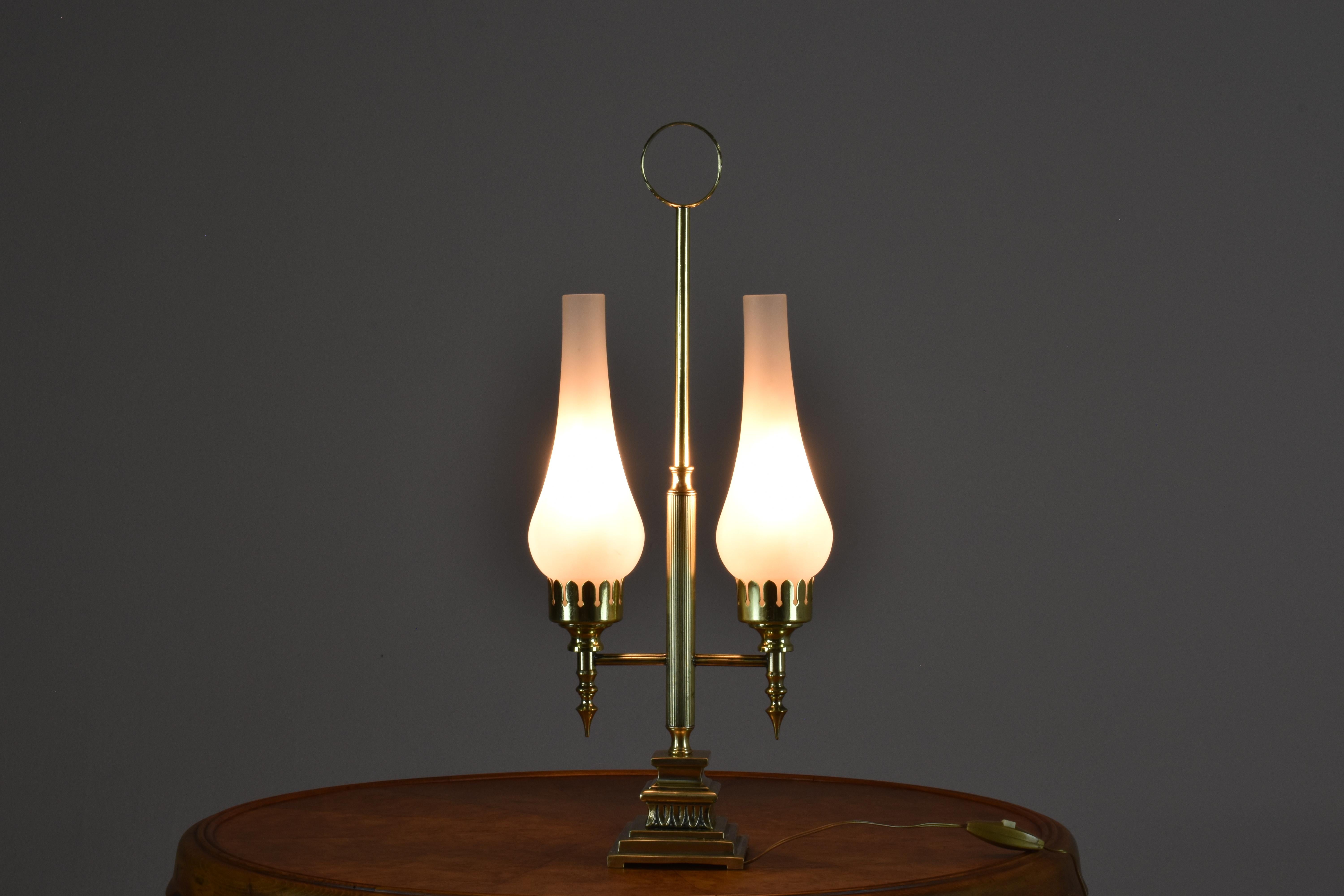  A 1960s Italian lamp that features two sanded glass shades. The intricate brass structure in the centre is characterised by classic and ornamental Art Deco designs. It has elegant and geometric shapes, rich materials, and intricate detailing. The