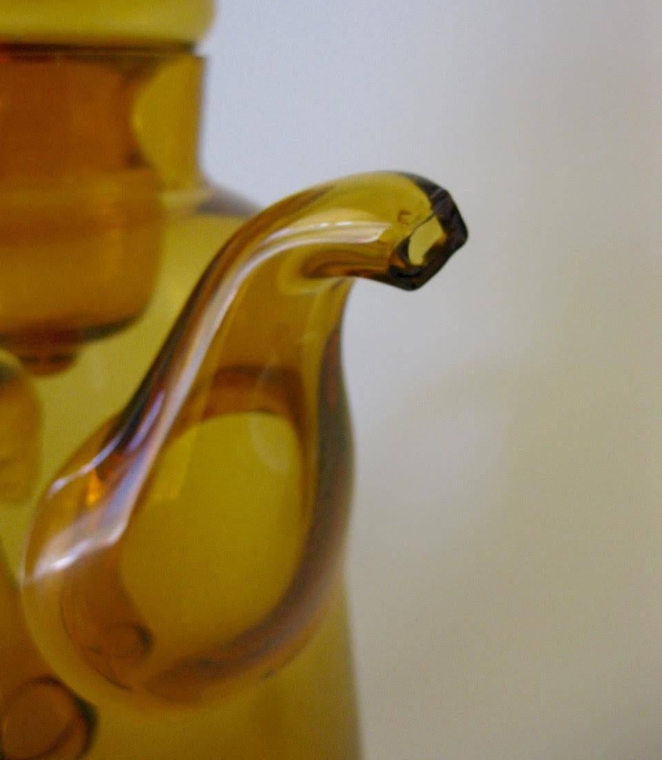 1940s lidded amber art glass teapot/lidded pitcher by Empoli Italy is done in an amber colored glass. The lid looks to be handblown, with an applied handle and spout.