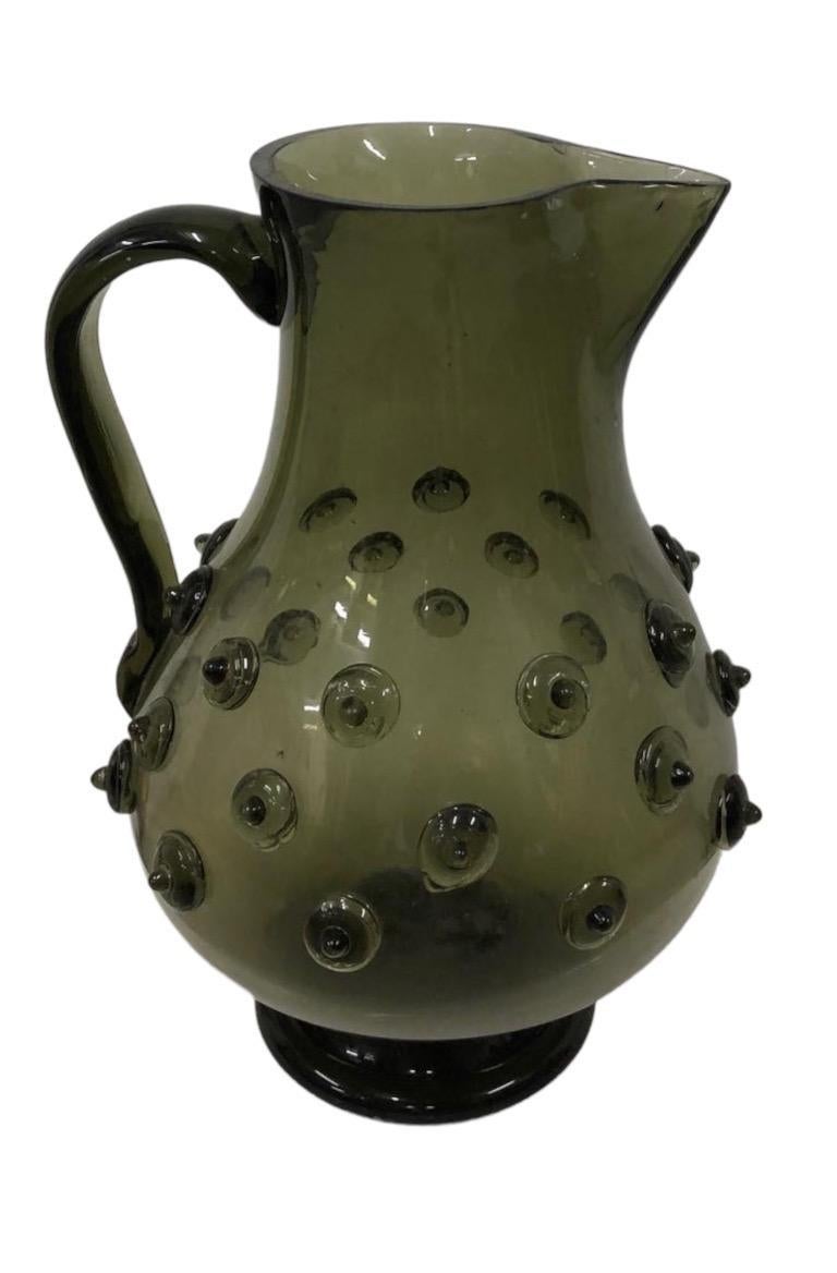 1940s Italian green glass pitcher with raised glass details.

Property from esteemed interior designer Juan Montoya. Juan Montoya is one of the most acclaimed and prolific interior designers in the world today. Juan Montoya was born and spent his