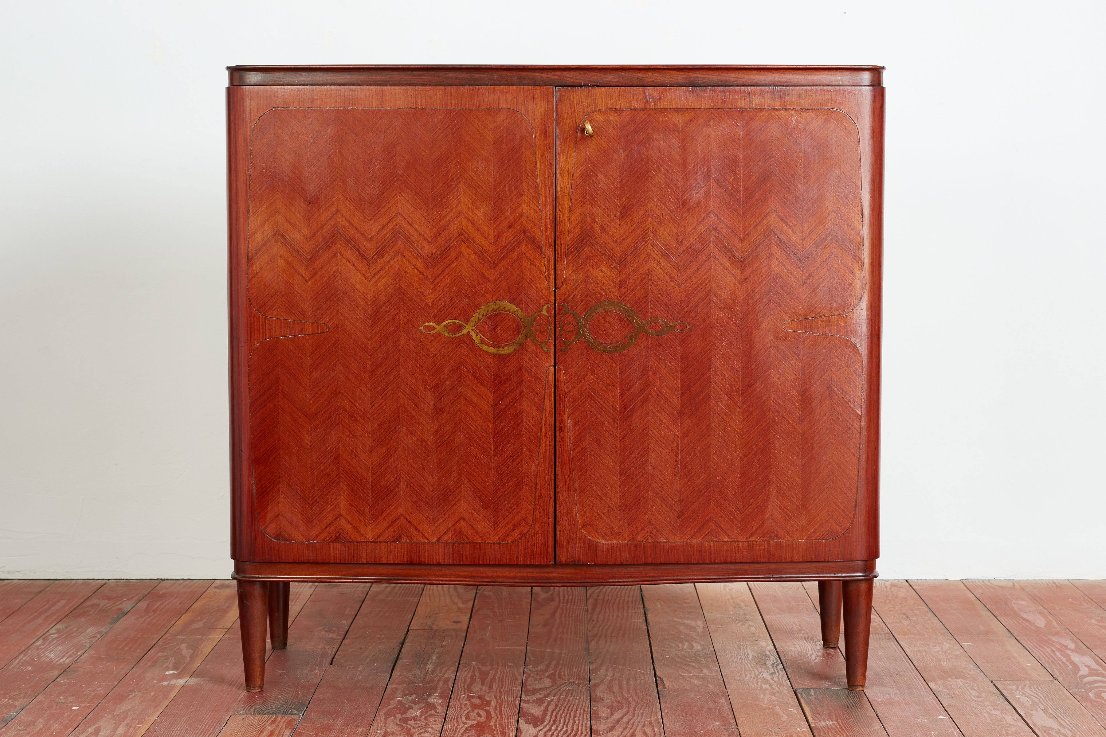 1940's Italian Mahogany wood bar cabinet with ornate herringbone patterned doors with inlay detail.  Doors open to reveal mirrored cased through out interior with brass and glass shelves for bottles and glasses.  Center shelf has multiple pull out