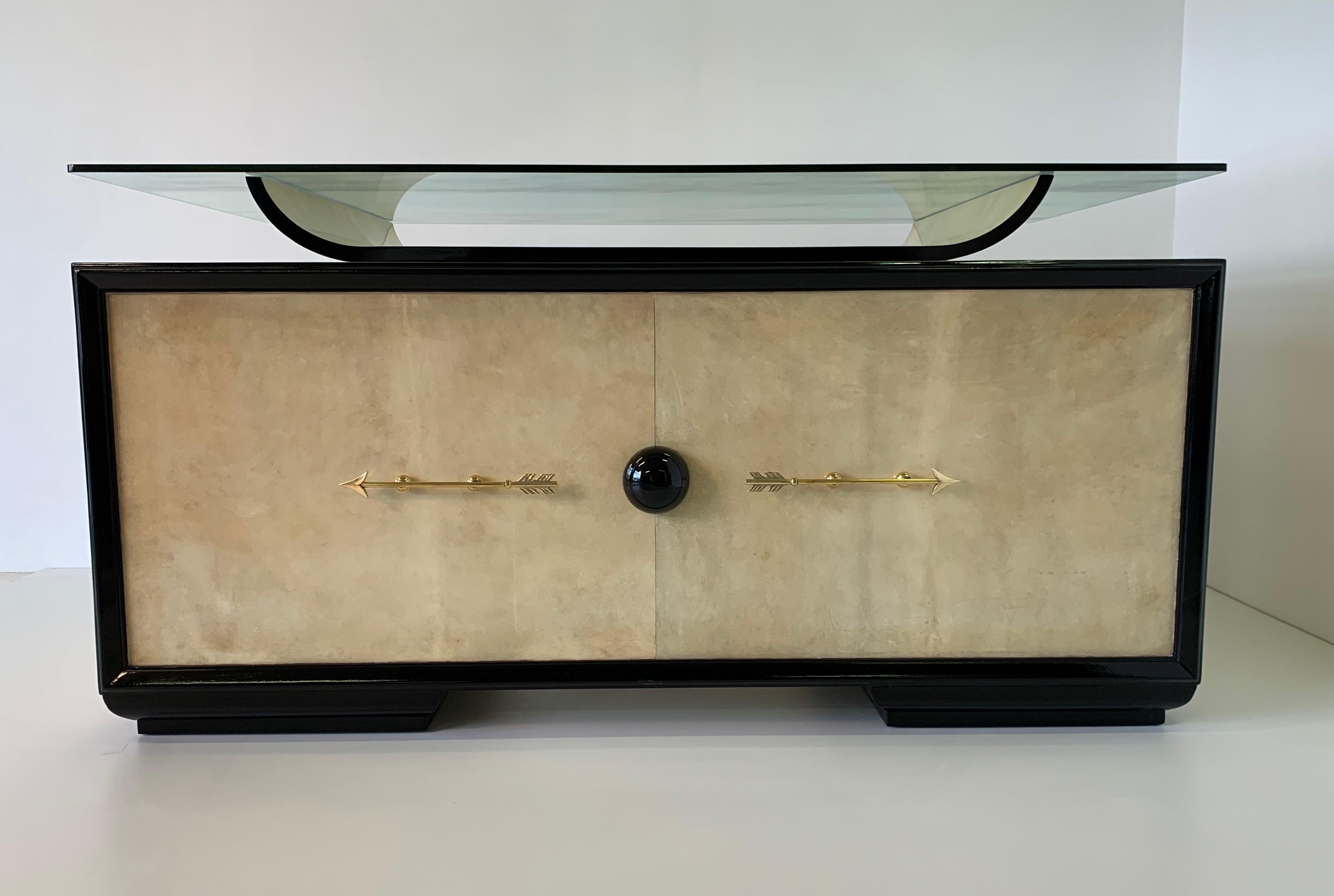 Italian Art Deco desk from the 1940s totally covered in parchment.
The profiles are black lacquered while the handles and the two arrows are in brass, the top is in original glass.
The design is attributed to Osvaldo Borsani.
Completely restored.