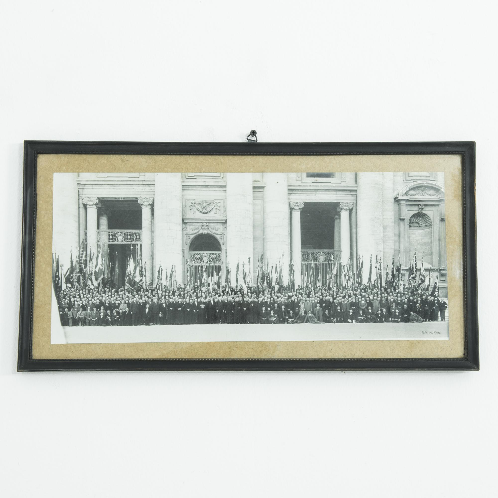 A black and white photograph in a wooden frame from 1940s Italy, depicting a parade or official gathering. The photograph would have been taken during the years of the Mussolini dictatorship — the deliberate framing of the Neoclassical architecture