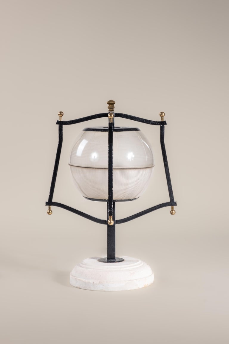 This 1940s table lamp features a lantern-style cage made of painted metal, with spherical brass finials. A satin opal glass globe encases the bulb. Made in Italy. Condition consistent with age and use. Newly rewired.

Materials: metal base, opal