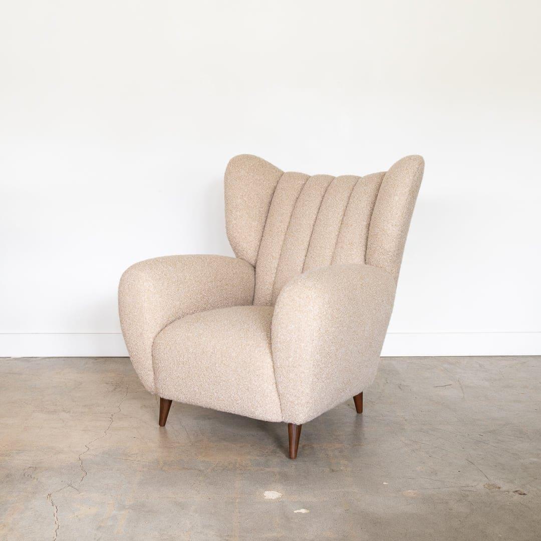 Incredible vintage Italian wingback armchair from the 1940's. Large and curvy seat newly upholstered in greige bouclé. Four wood tapered feet with dark stain. Beautiful from all angles and extremely comfortable. Second chair available to make a pair