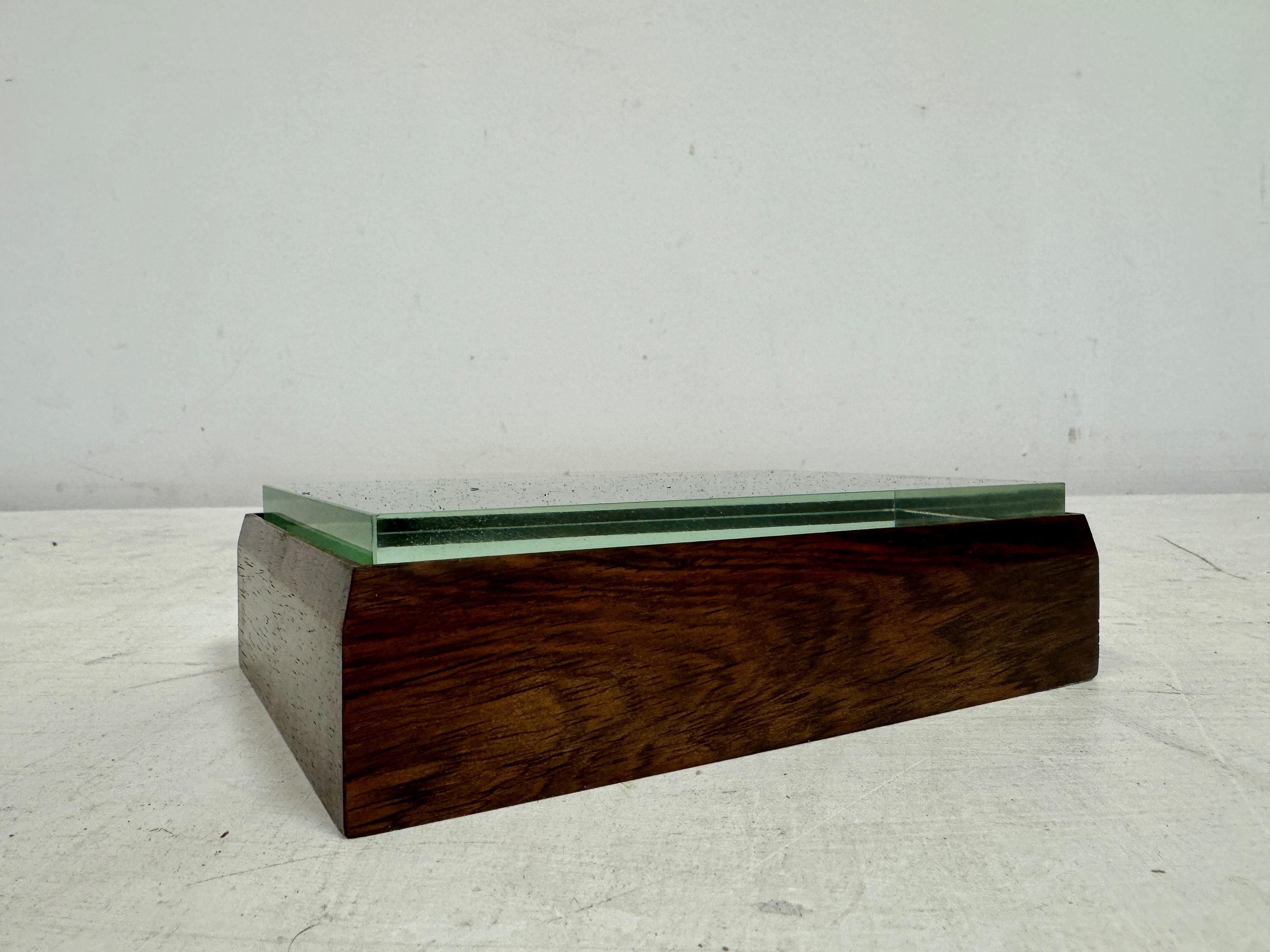 Esta elegante caja de baratijas de Fontana Arte muestra un diseño refinado que combina materiales lujosos y una estética minimalista. La base de la caja es de madera noble, con un tono profundo y cálido y un veteado muy natural. La parte superior de