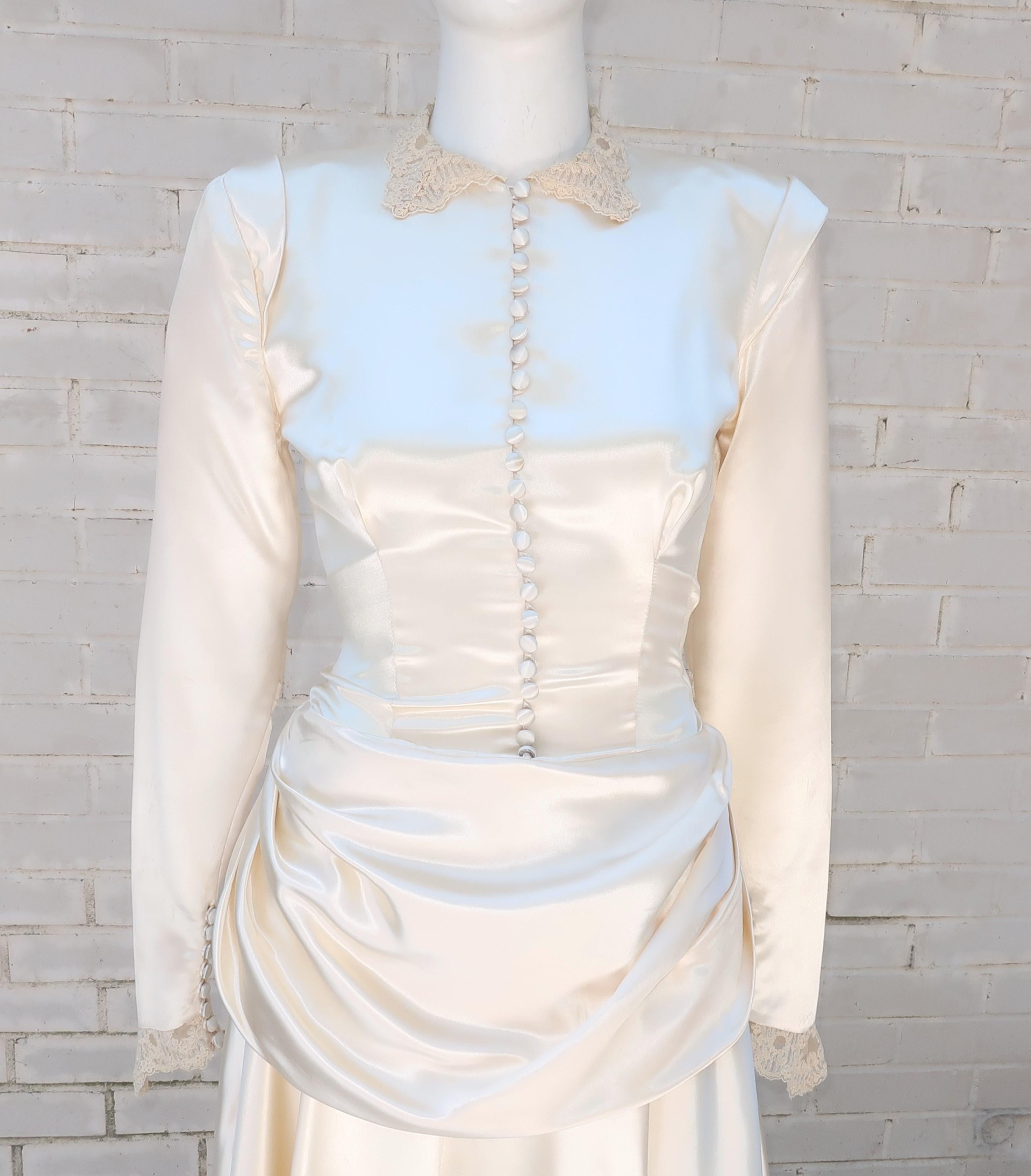 Here comes the bride!  And she exudes post war glamour in a 1946 ivory satin wedding gown with a form fitting bodice yielding to a draped peplum and bustle which anchors a built-in train.  A row of satin covered buttons from neck to waist and French