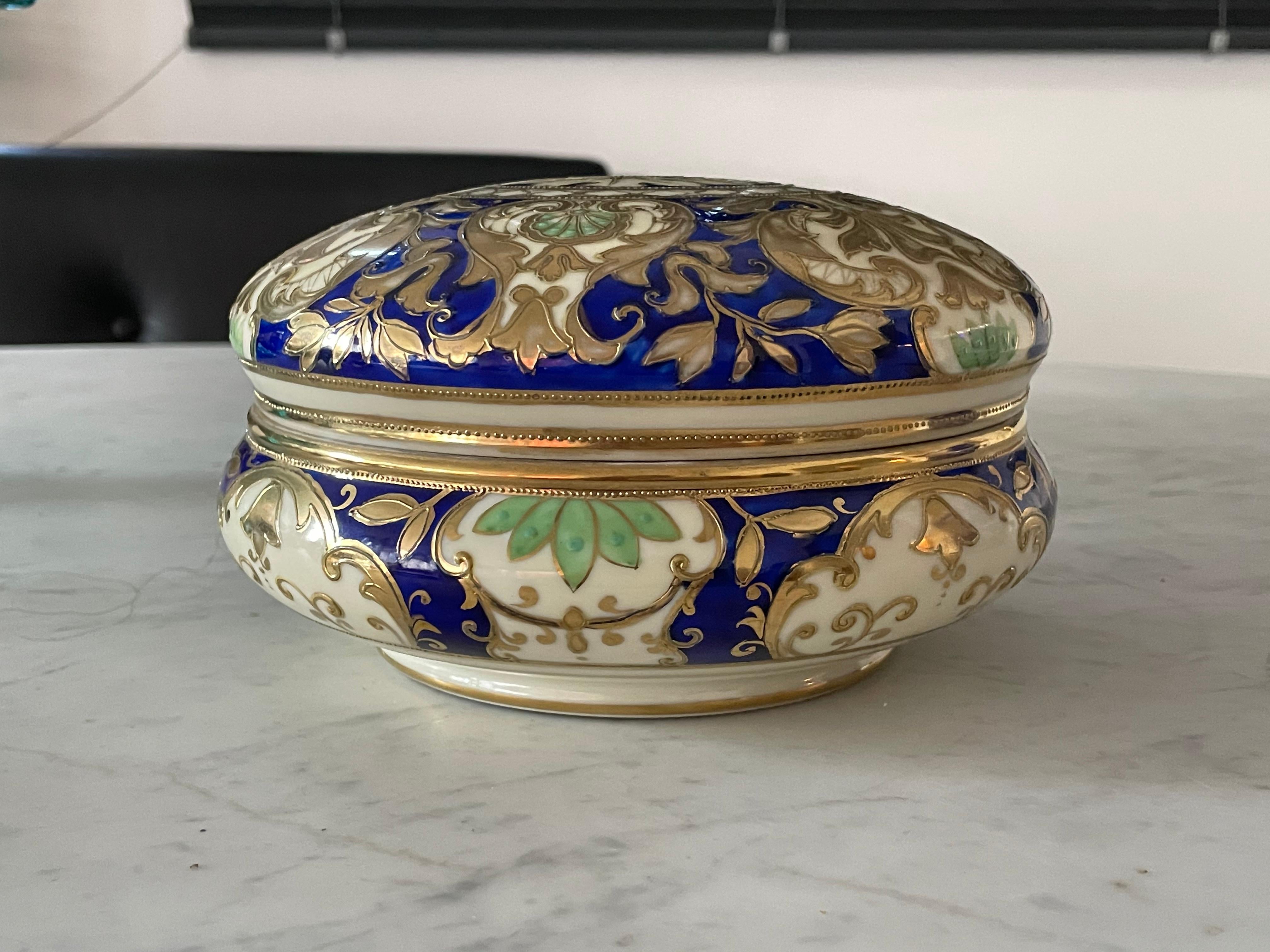 A collectible 20th century vintage Japanese porcelain bowl by Noritake with intricate gold leaf, blue and green hand-painted ornaments. 
A decorative object which can be used as tableware for sweets or chocolate (bonbonniere) or as a trinket