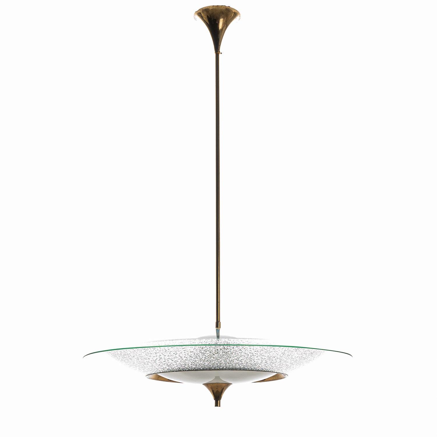 Questa elegante lampada a sospensione è composta da una struttura in ottone, un grande riflettore in vetro trasparente sulla parte superiore, un vetro fumé in basso al centro circondato da una parabola ad anello in vetro ruvido. Al centro 3 prese