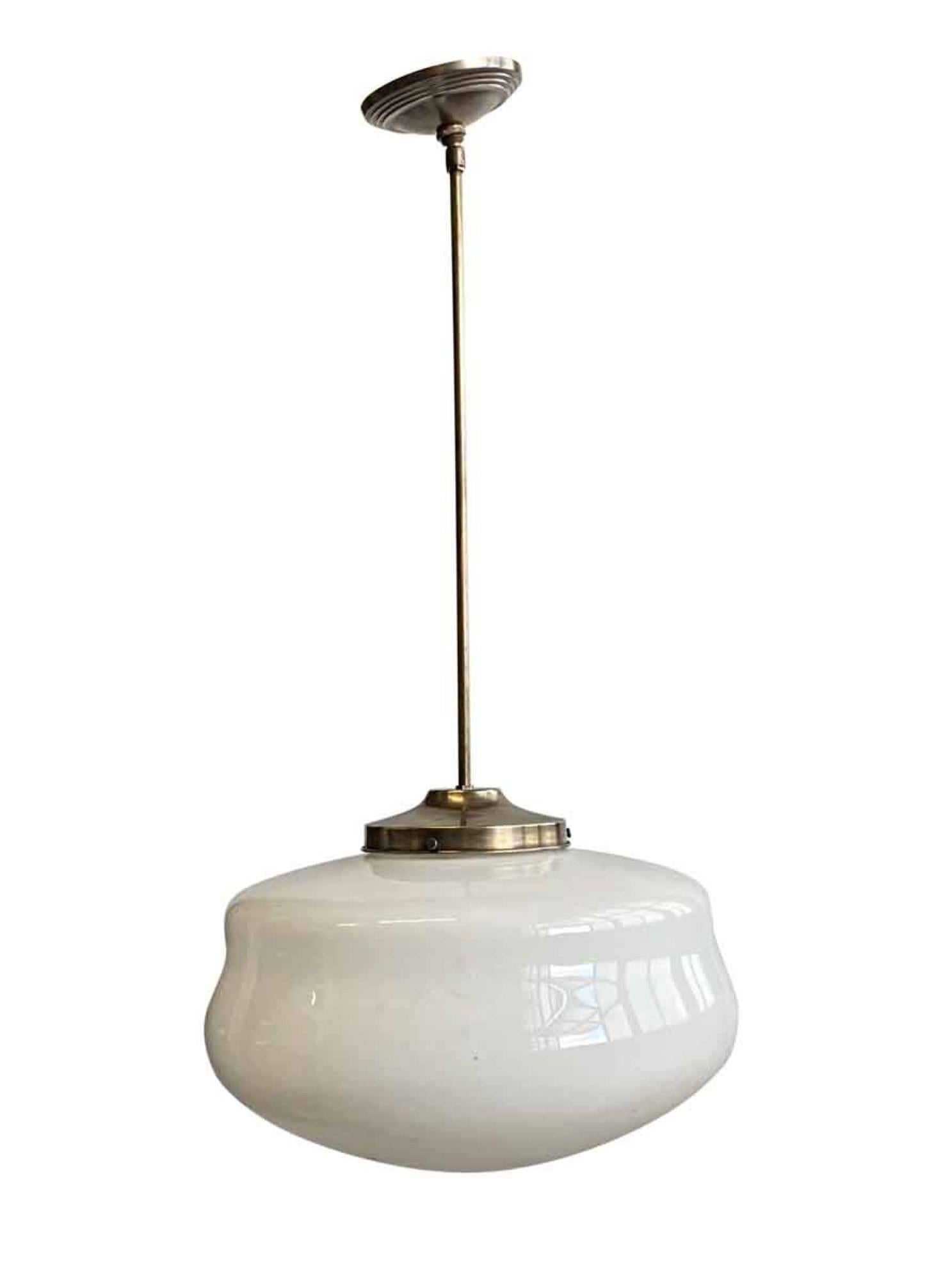 1940s schoolhouse globe pendant light mounted on a newly made brass pole fitter. Small quantity available at time of posting. Priced each. This can be viewed at our Scranton, Pennsylvania location. Please inquire for the exact address.
