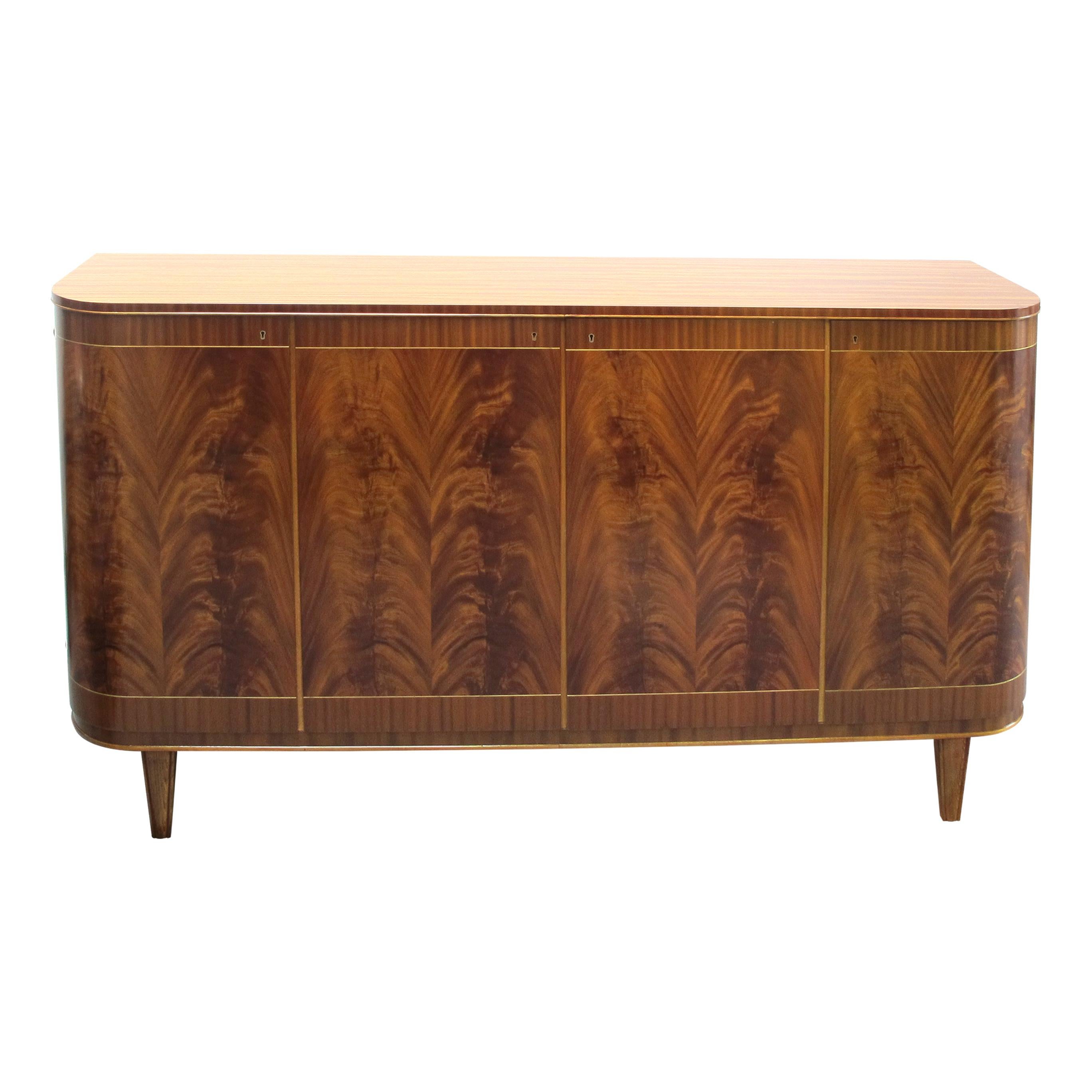 One of the first things that catch the eye is the sideboard's distinctive curved edges, which add a touch of sophistication to its overall appearance. The use of Cuban Mahogany with beautiful flame patterns on the front doors imparts a touch of