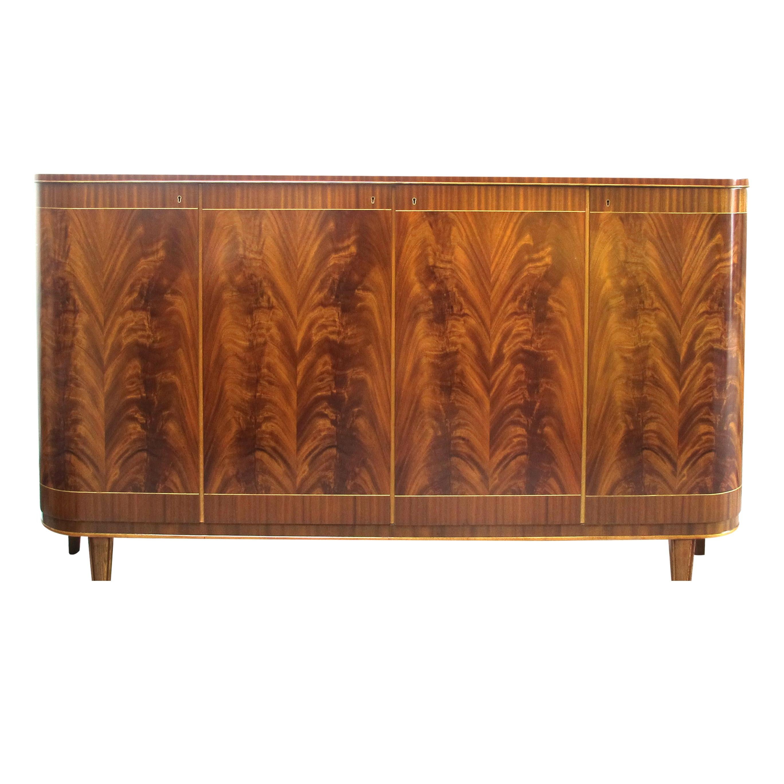 One of the first things that catch the eye is the sideboard's distinctive curved edges, which add a touch of sophistication to its overall appearance. The use of Cuban Mahogany with beautiful flame patterns on the front doors imparts a touch of