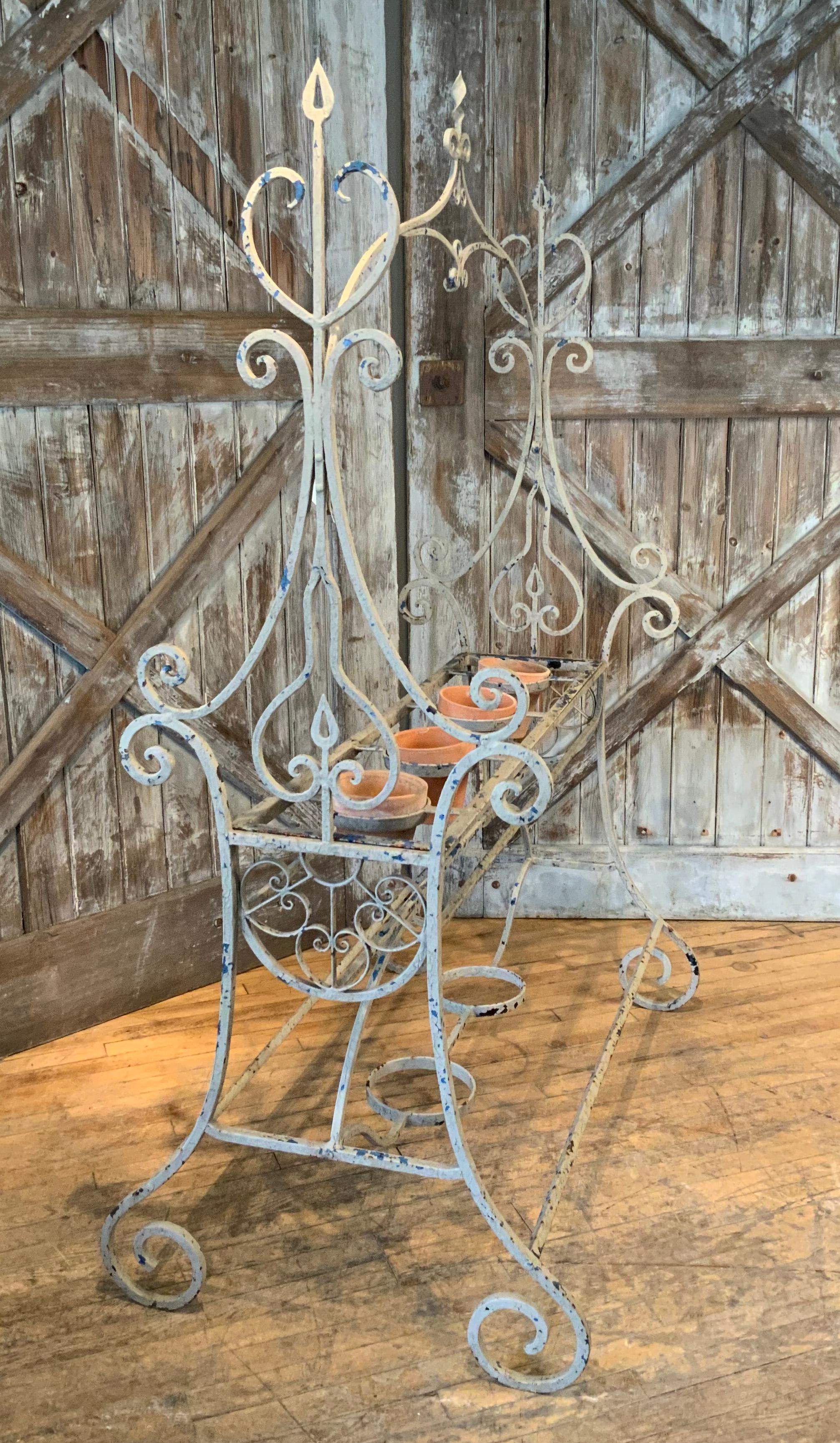 A very impressive and large 1940's wrought iron plant stand by Salterini. made of the highest grade wrought iron, very well made and heavy, with a scrolled base and sides, with a curved finial in the center top. the stand has circular supports for 4