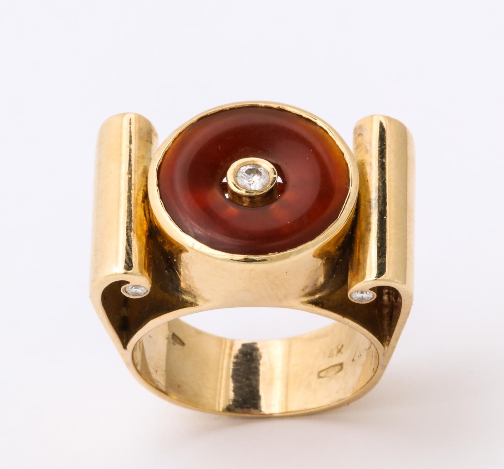One Unisex Geometric And High Style Ring Created In 14kt Yellow Gold. Ring Is Centering One Reddish Honey Colored Lifesaver Cut Carnelian Stone And Bezel Set With One .7Ct Full Cut Diamond In The Center. Ring Is Further Flanked By Four Bezel Set