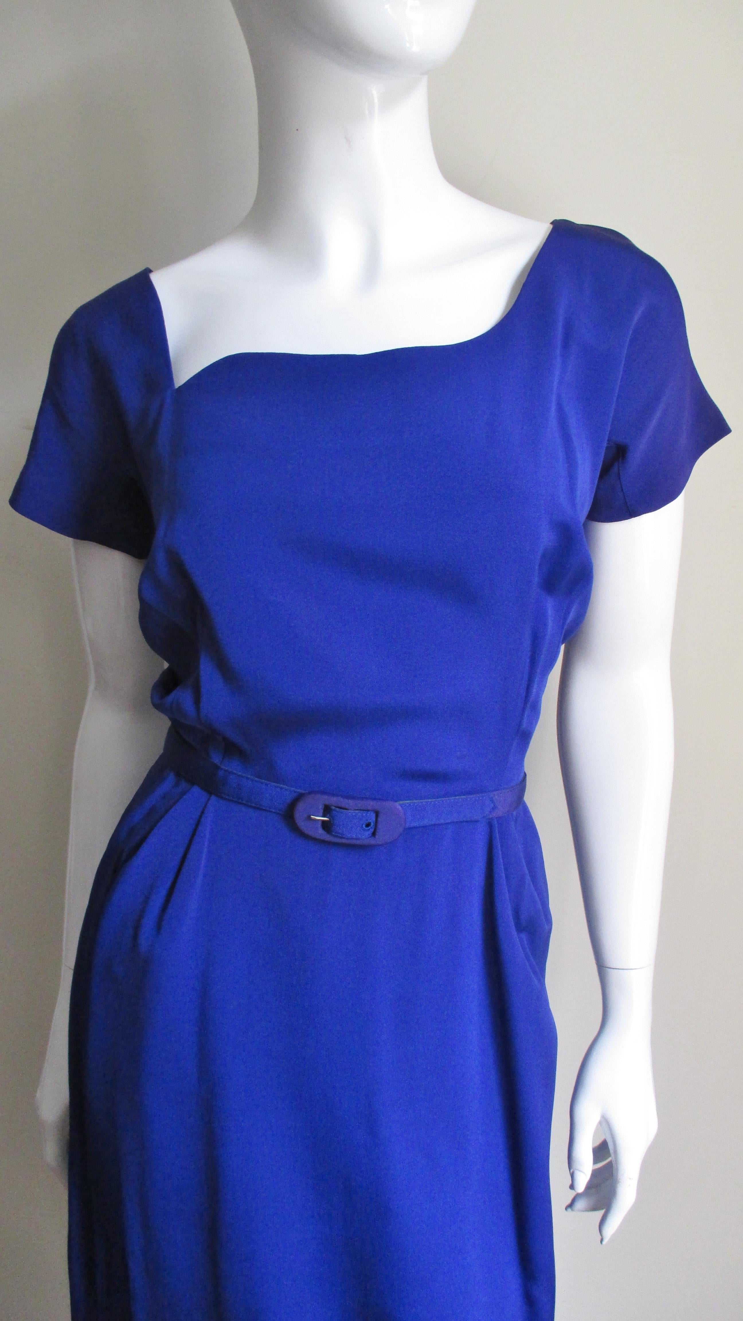 A rare unworn 1940s dress in purple silk from Lilli Ann.  It has an asymmetrical front neckline with a V in back, short sleeves and a straight skirt with a back kick pleat.  The dress comes with a matching belt, is fully lined and closes in the back