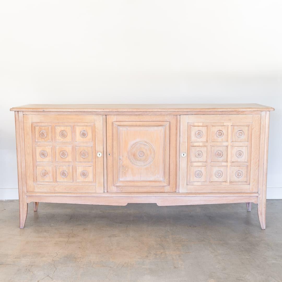 Incredible long wood sideboard in the style of Charles Dudouyt from France, 1940's. Beautiful carved wood squares with circle detail on cabinet doors and carved tapered legs. Newly refinished in a light cerused oak color. Three sections each with a