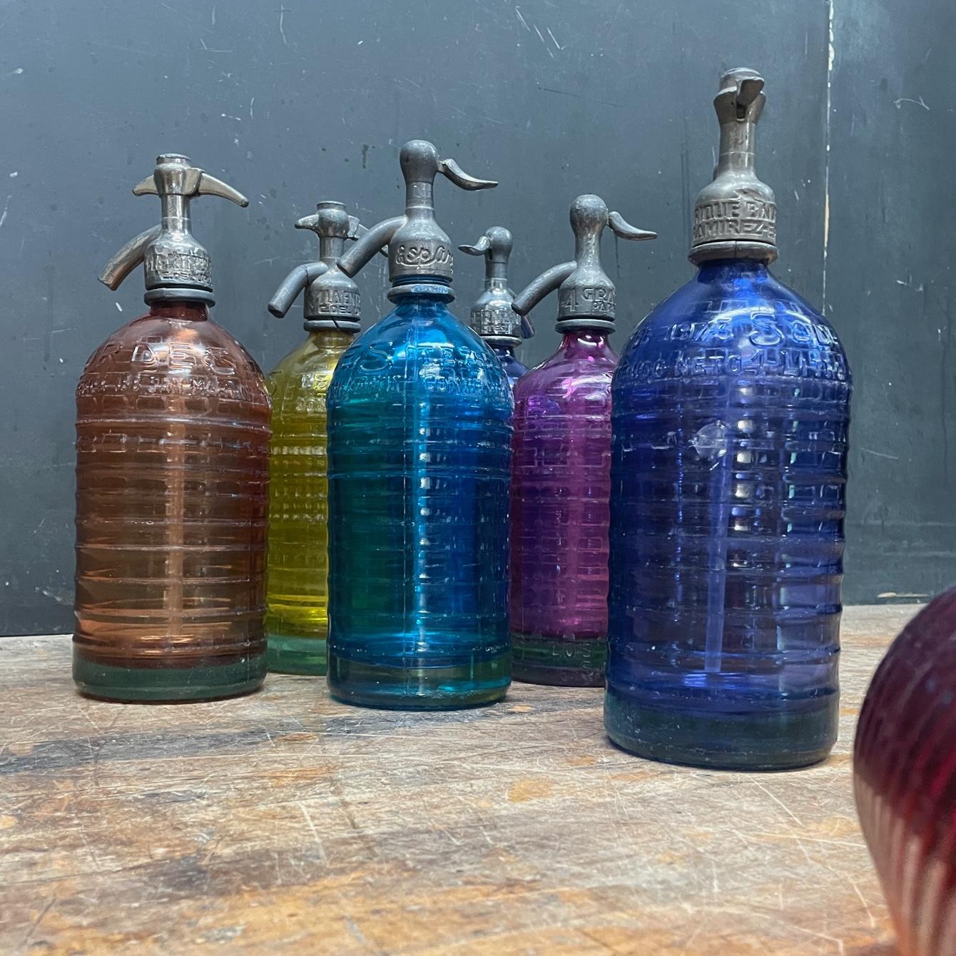 A beautiful very old Lourdes Argentinian seltzer bottle collection. Very colorful, even with a pink one, which is a color we have never seen. These are Sold as Non-Function for decoration.