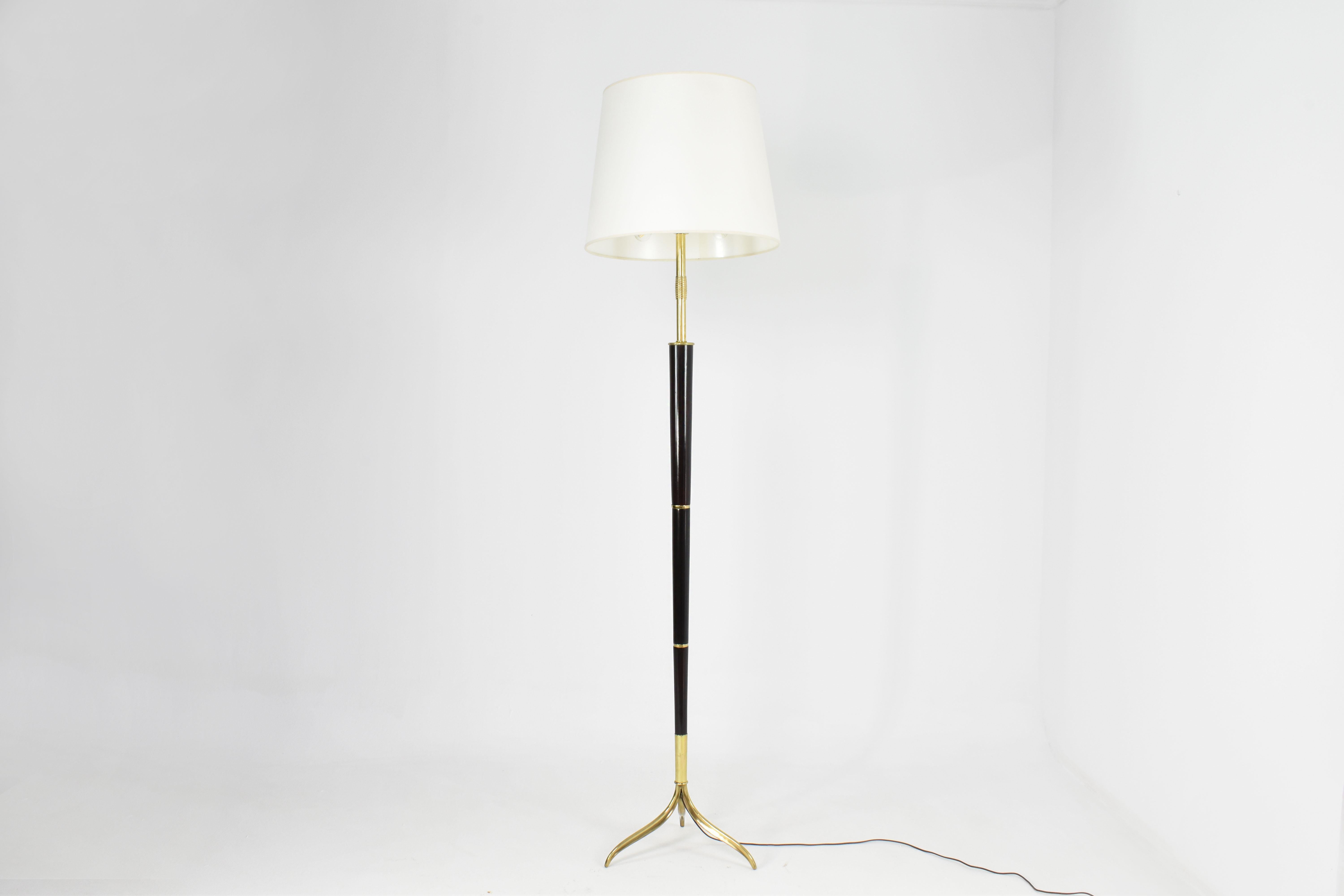 A very tall and elegant 1940s Italian vintage floor lamp designed by Giuseppe Ostuni and exceptionally handcrafted out of wood and brass. The piece stands on a sleek tripod base. The brass details combined with the warm veneer wood create an