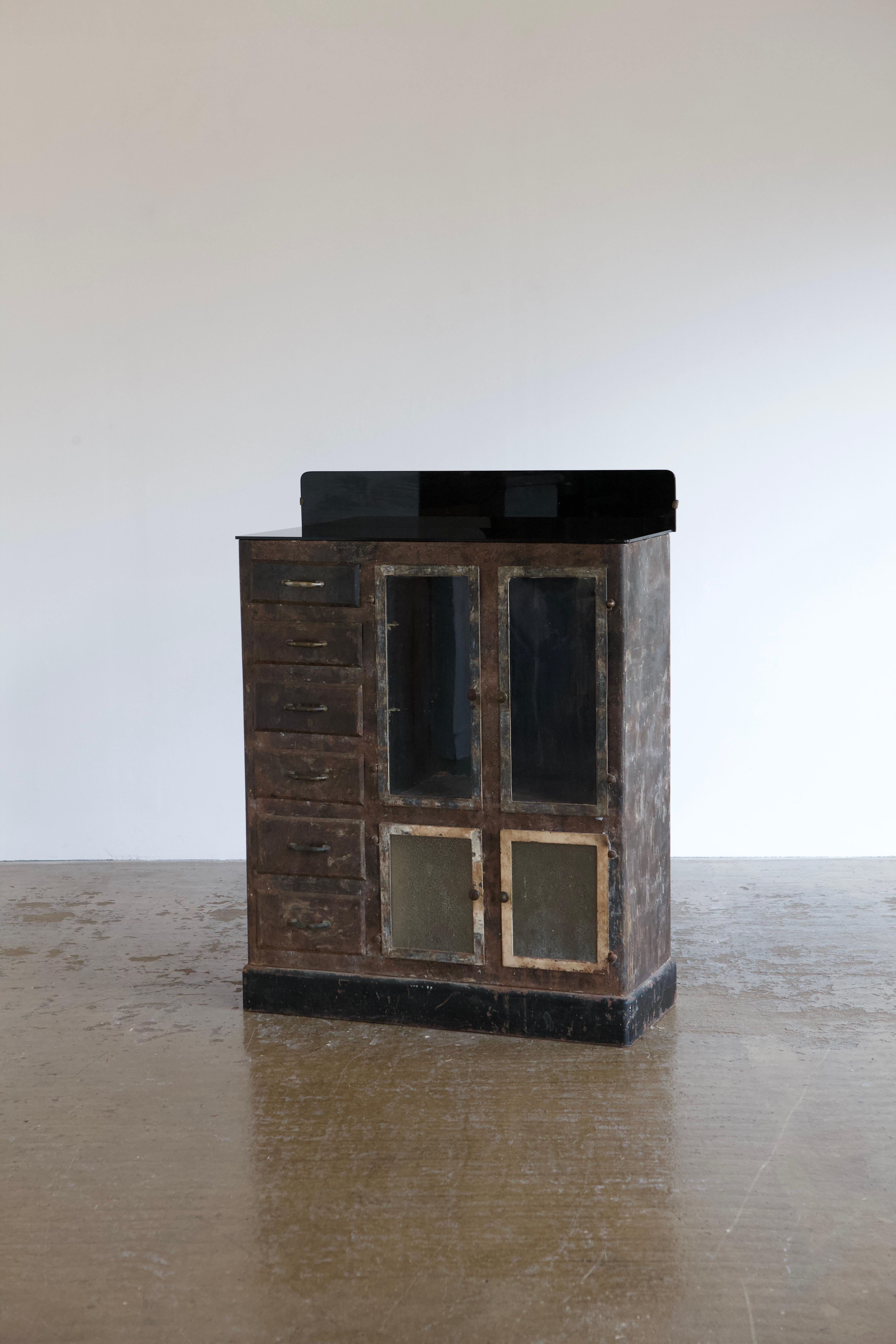 An absolutely wonderful and unique example of a mixed metal cabinet with incredible patina and superb details. The cabinet features monochrome finish and mixed glass on the doors and brass handles throughout. It also has 6 drawers and two levels of