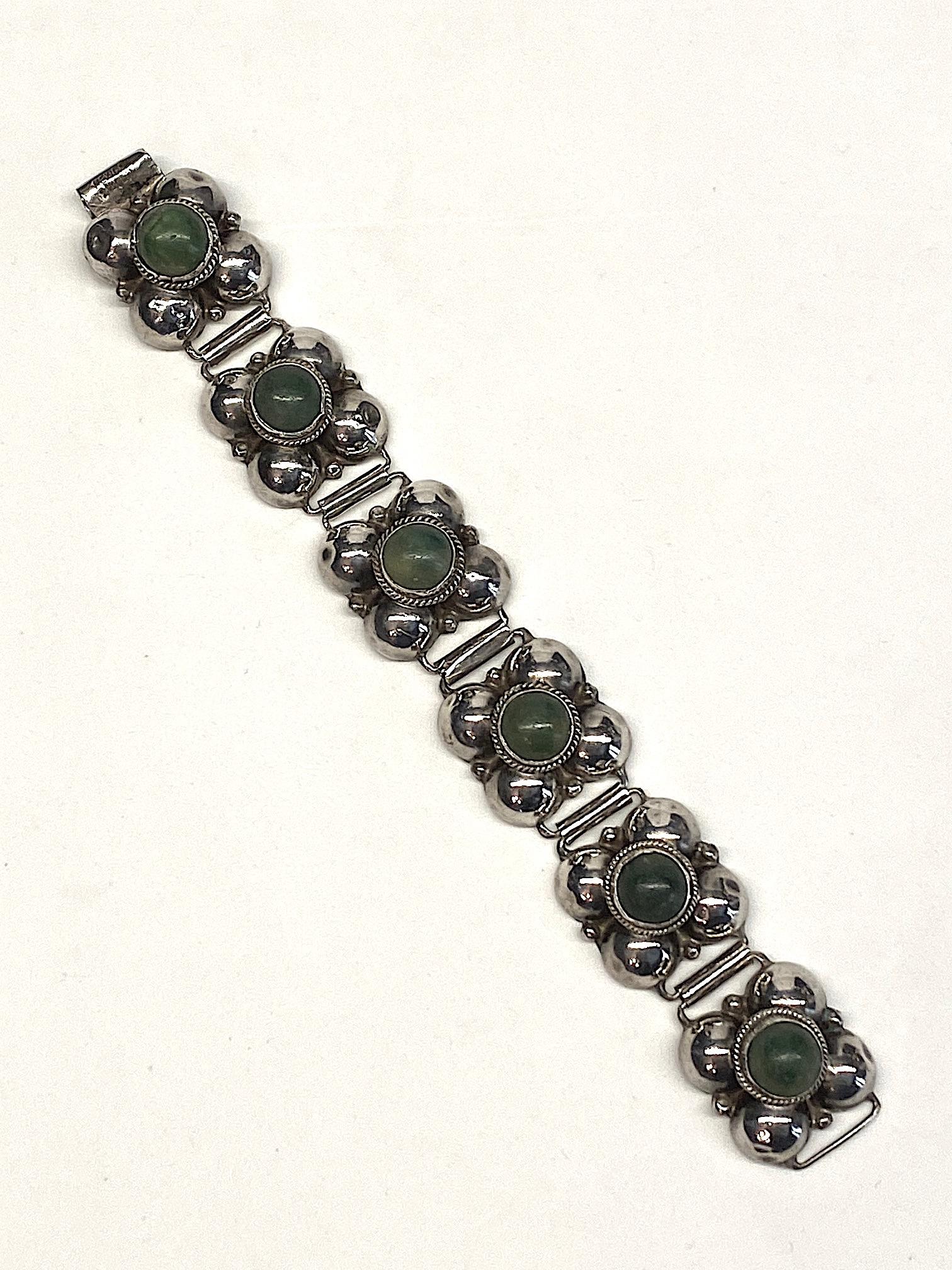 This Mexican 1940s silver bracelet is comprised of six links .88 of an inch square. Each link is set with a central 11 mm green calcite cabochon on top and has a solid plate on the back. The bracelet measures .88 of an inch wide, 7.5 inches long and
