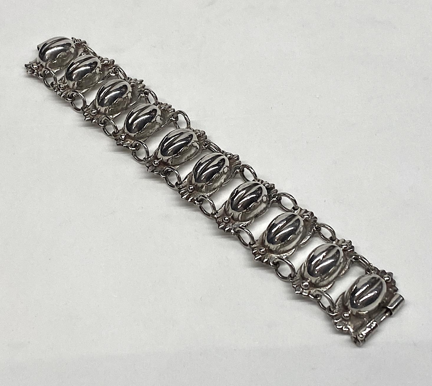 Sterling silver coffee bean bracelet from Mexico from the 1940s. The bracelet is hand made and constructed of ten large links and nine pair of round links. The large links consist of a bottom scallop edge base mounted with an oval domed coffee bean.