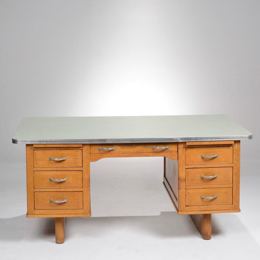 American-made Mid-Century Modern tanker desk in good condition, constructed of oak with a Formica top and steel handles. Maker's mark inside center drawer. Standard Furniture Co., built in Herkimer, NY, circa 1940.