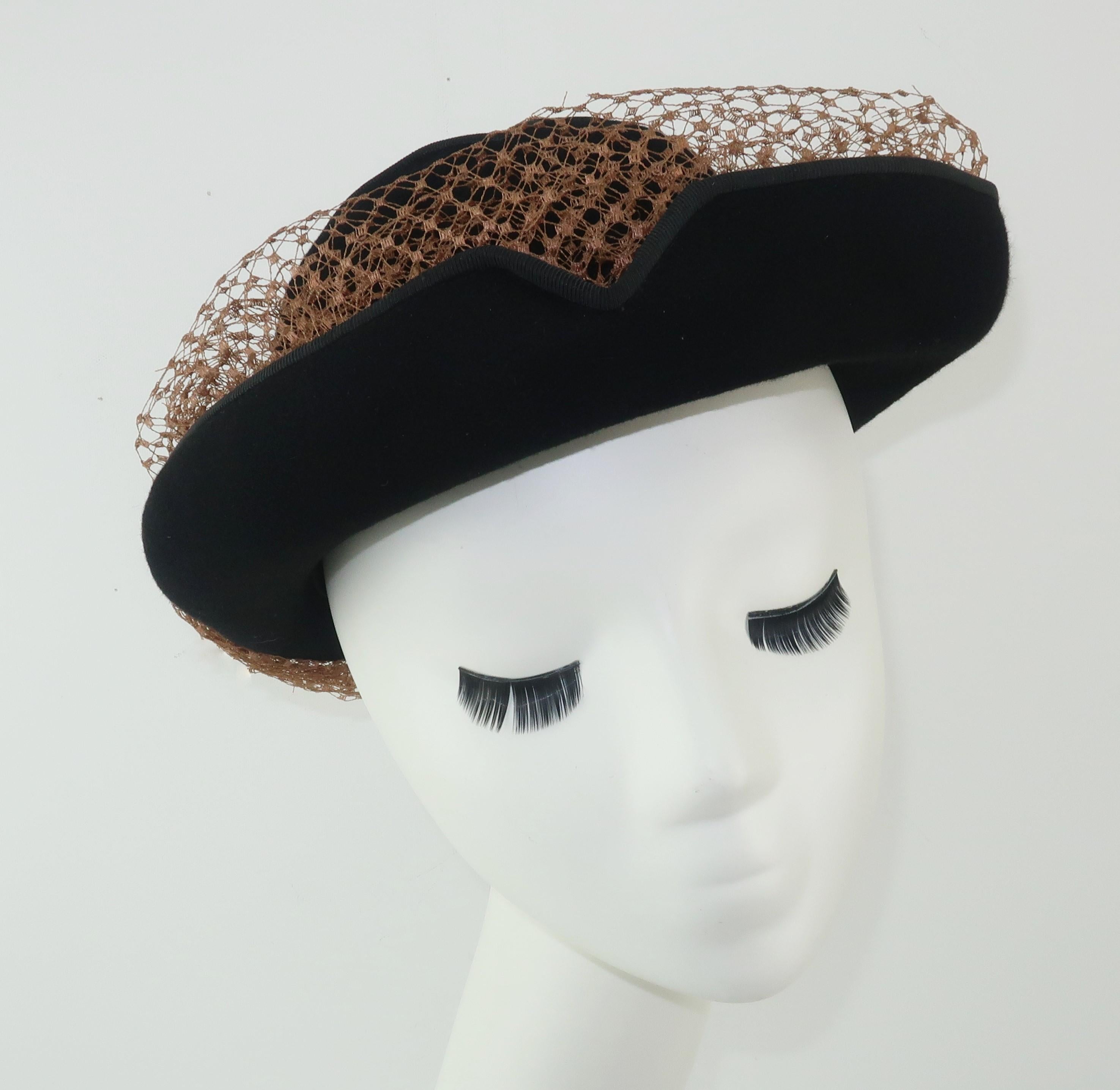A stylish 1940’s Miriam Lewis black wool felt hat with a vented crown, grosgrain trimmed brim and contrasting camel color netting with bow.  The unique rolled brim is nicely detailed with v-shaped cuts that add visual interest and serve as a channel