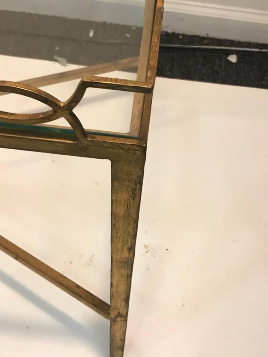 Gilt metal rectangular coffee table with frame of looped half circles and rectangles with a elongated x stretcher base connecting to four tapered legs. Designed in the 1940s in the manner of French designer Jean Royère. There is a clear rectangular