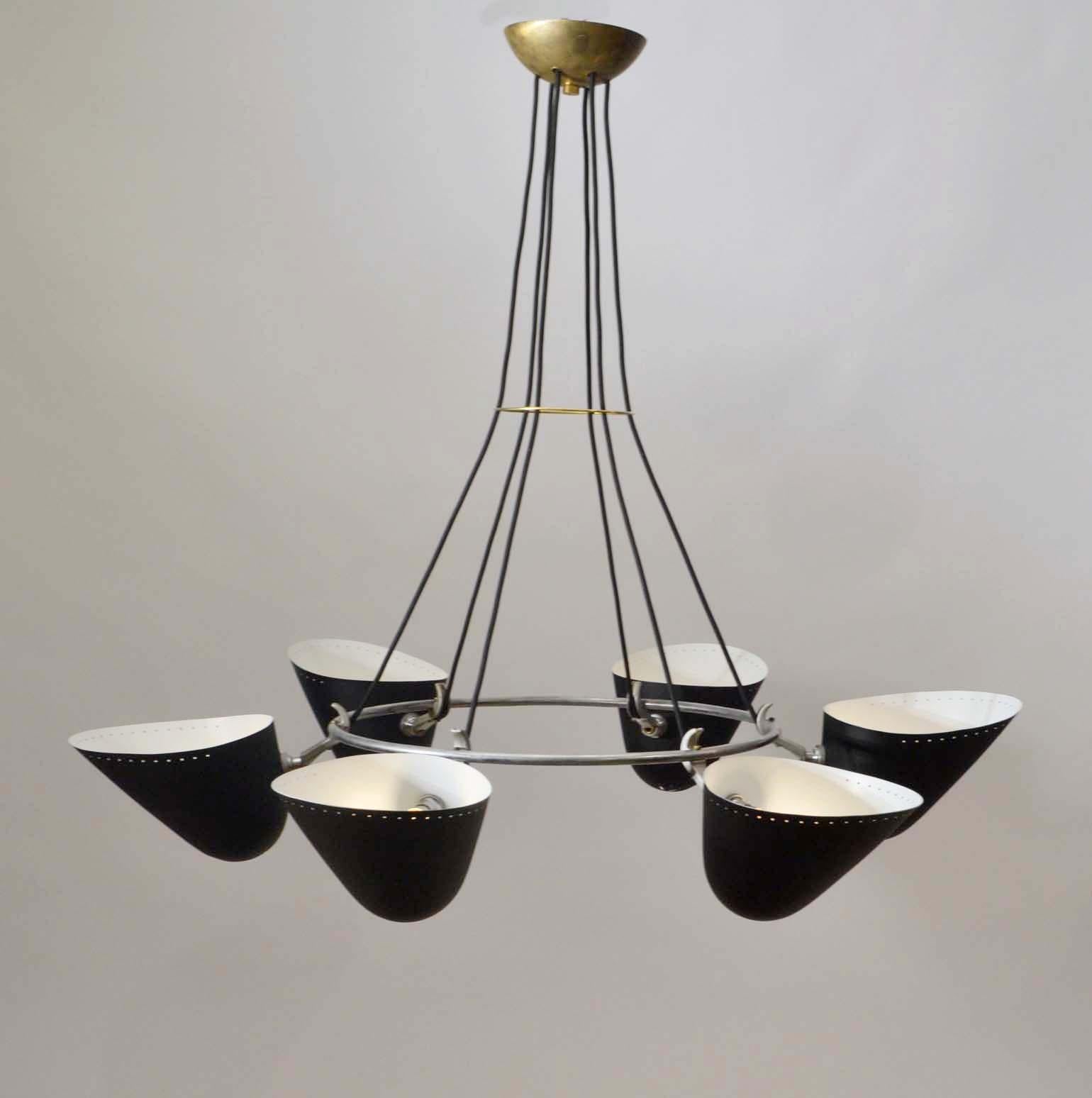 One of a pair  of original Mid-Century Modern six-shades black metal chandelier with perforated shades, attached to a chrome plated ring with chrome-plated machine joints. A brass ring holds the cords together and leads to a brass ceiling rose which