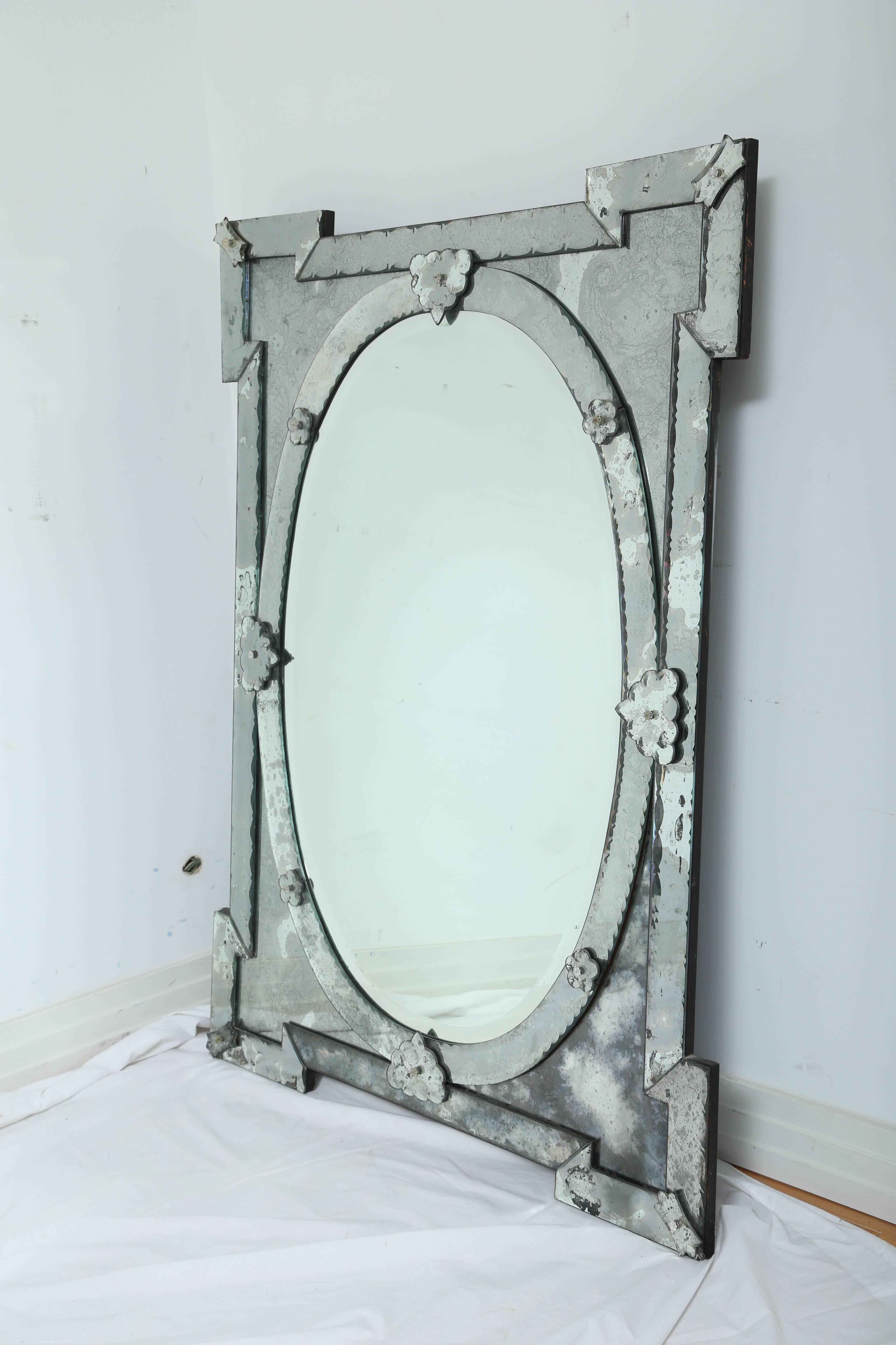 Exquisite large scale Venetian mirror with beveled edges and beautiful hand etched designs throughout. The mirror features a stunning oval center within a shield shaped frame.  Stunning Hollywood Regency, Baroque Revival  design, mixing well with