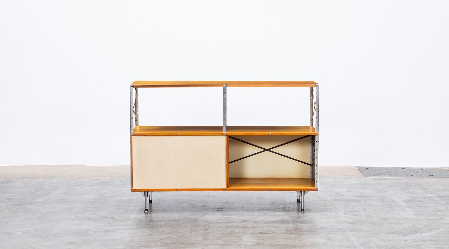Charles and Ray Eames storage unit featuring an open area in the upper section and two sliding doors in fiberglass in the lower section. The basic colour consists of beige, a red part at the back and a black piece at the side.The shelf comes in good